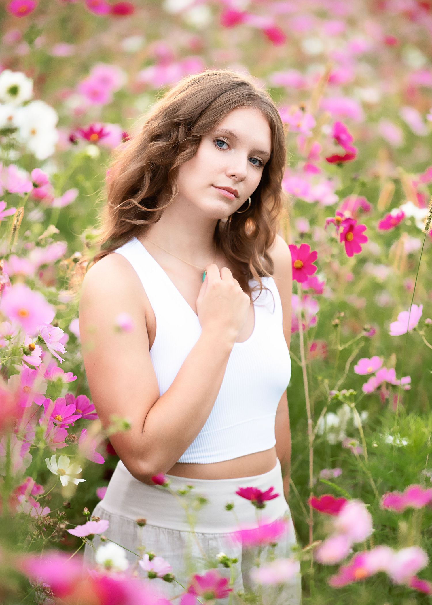 A dreamy portrait session in a field of pink cosmos flowers on a sunny day.