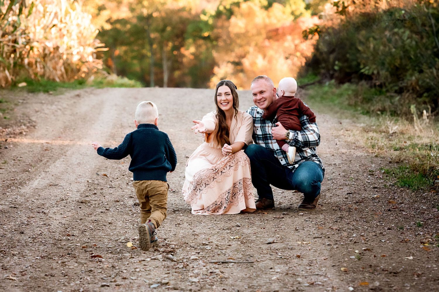 Family playing together on a dirt path during autumn sunset.