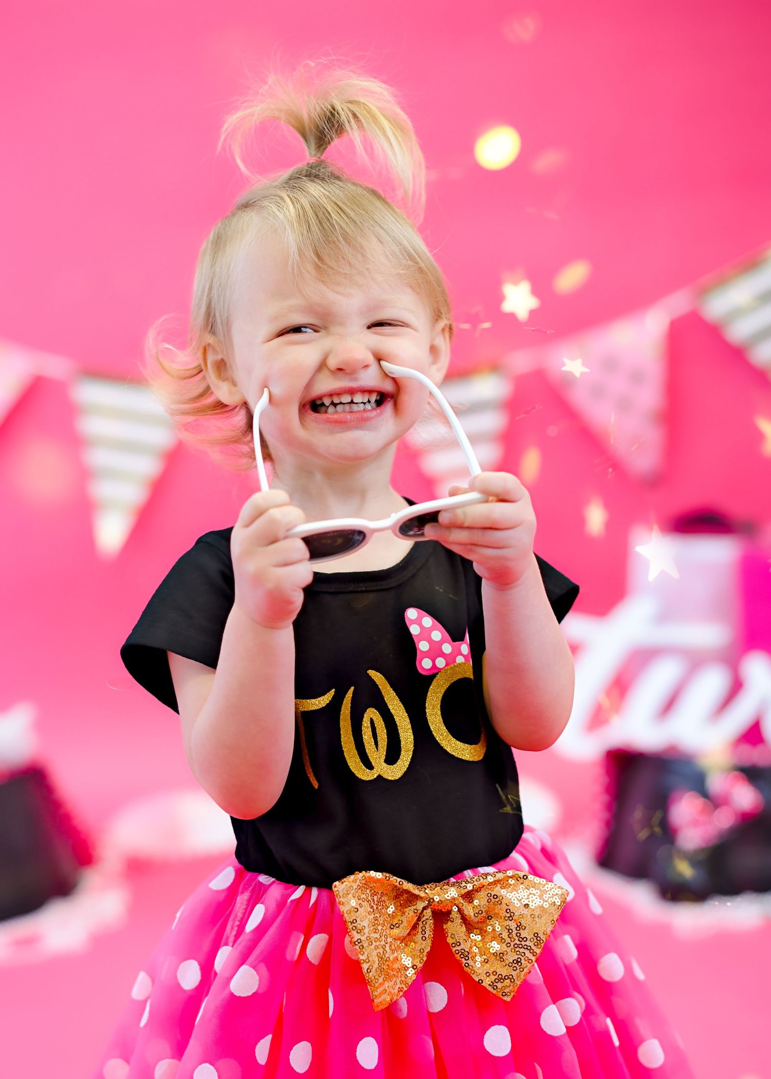 Joyful expression against pink background wearing polka dot tutu and black shirt.
