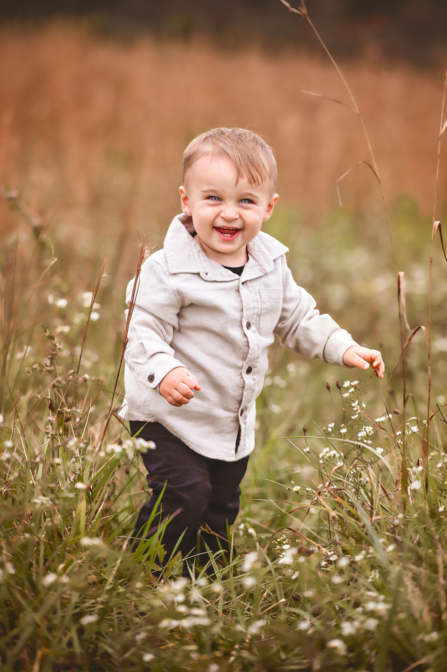 A joyful toddler runs and plays through a field of white wildflowers on a warm autumn day.