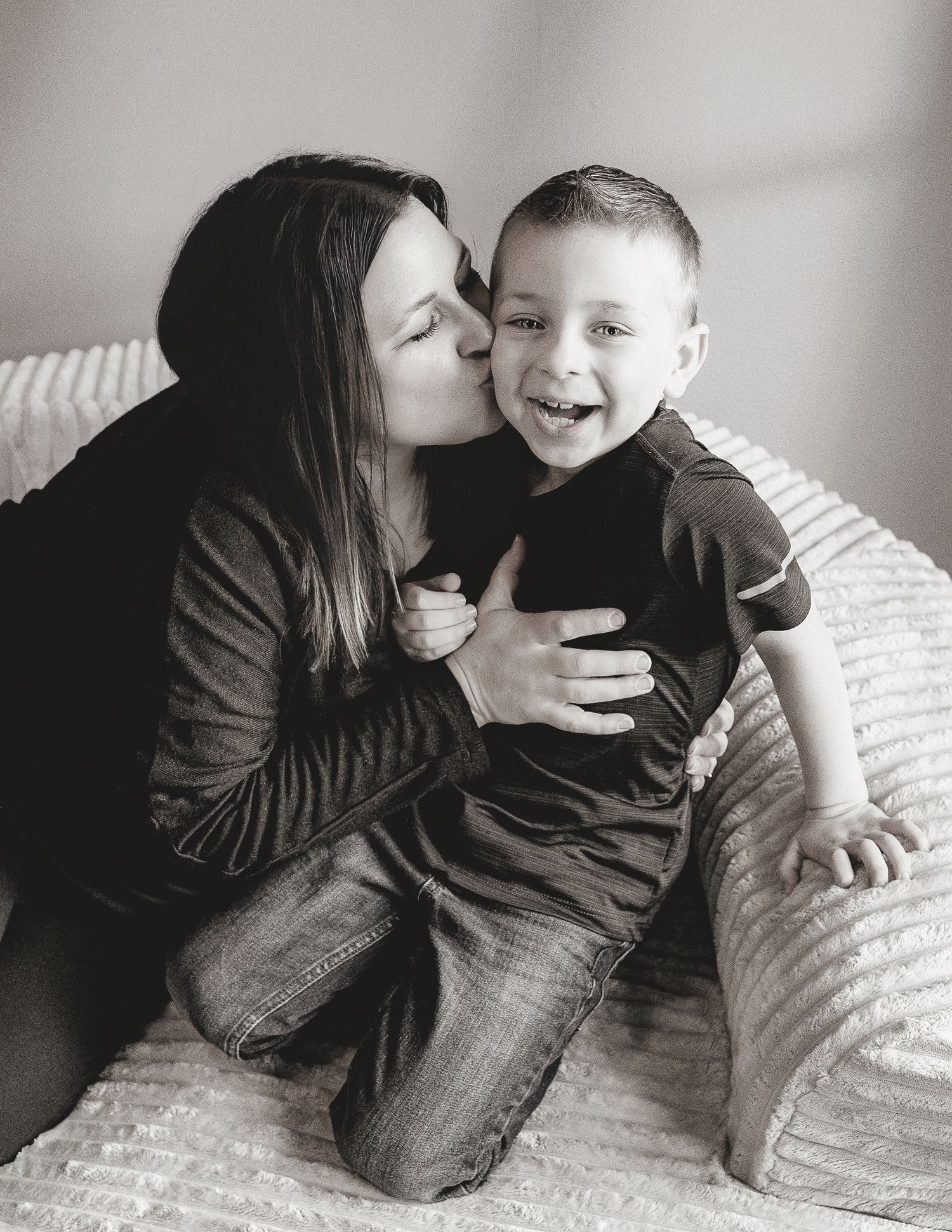 A heartwarming black and white photo showing a tender moment of affection and laughter on a cozy couch.