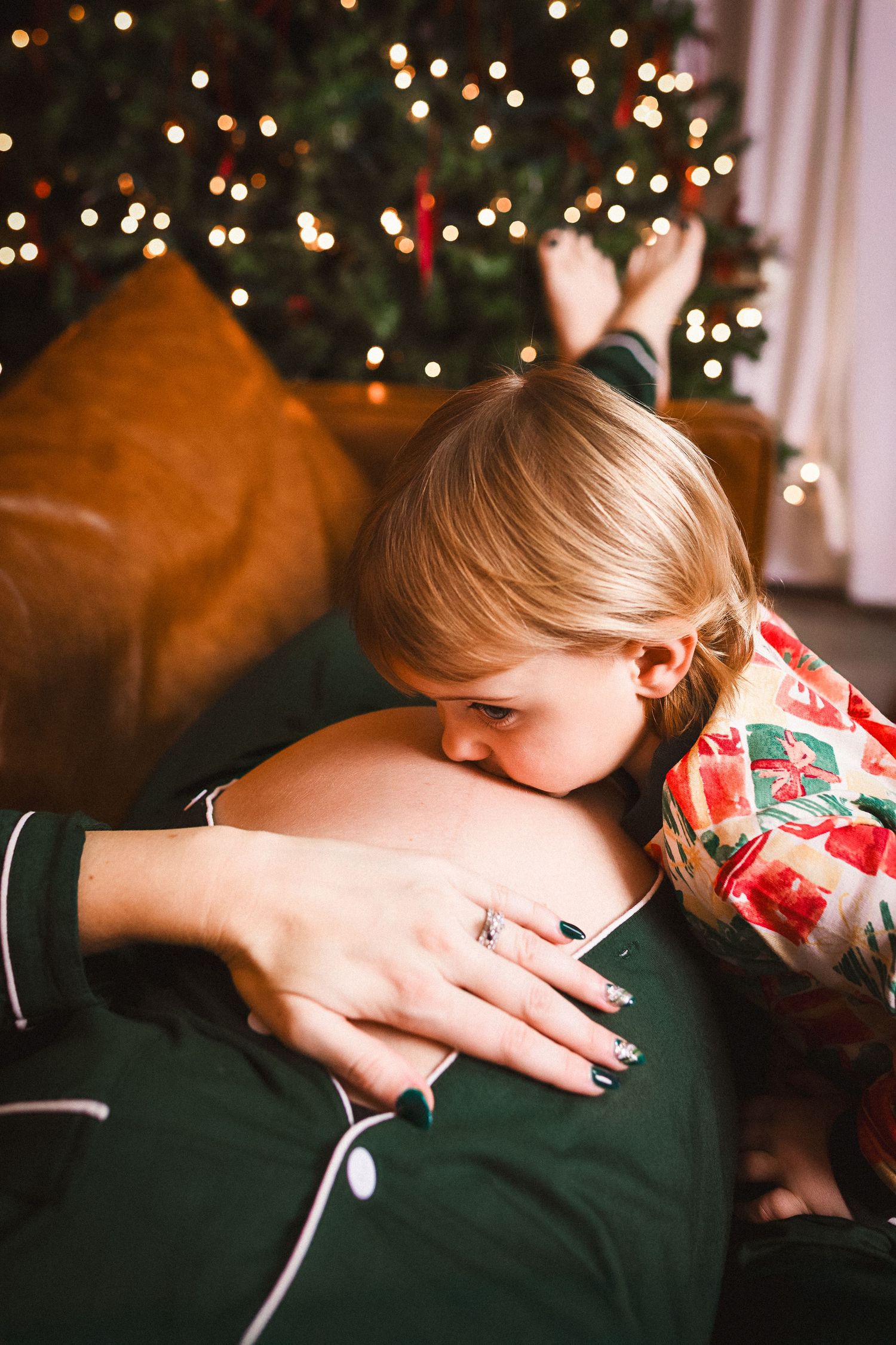 Intimate family moment captured by Christmas tree with bokeh lights.