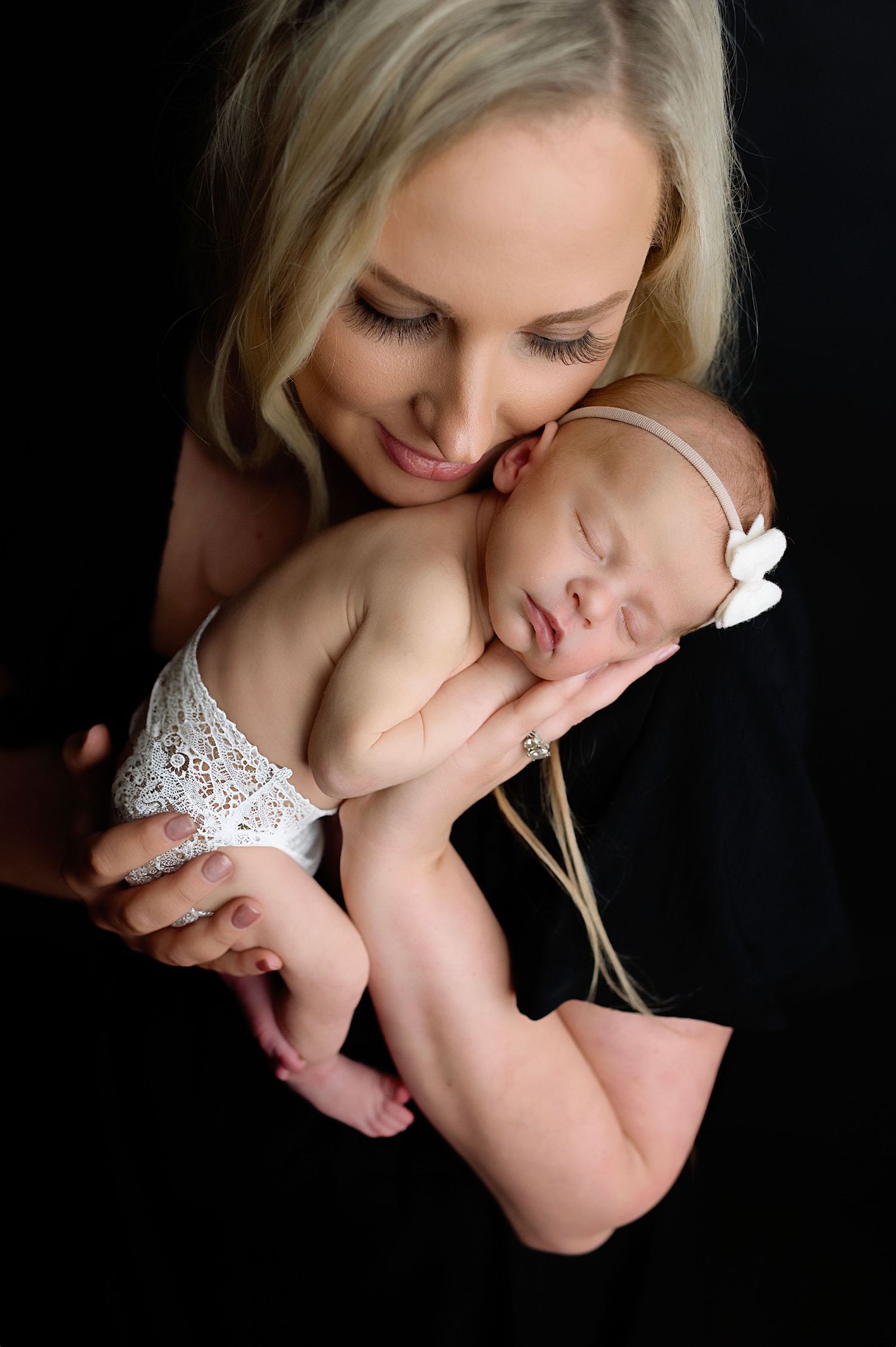 Intimate black and white portrait of mother holding sleeping newborn.