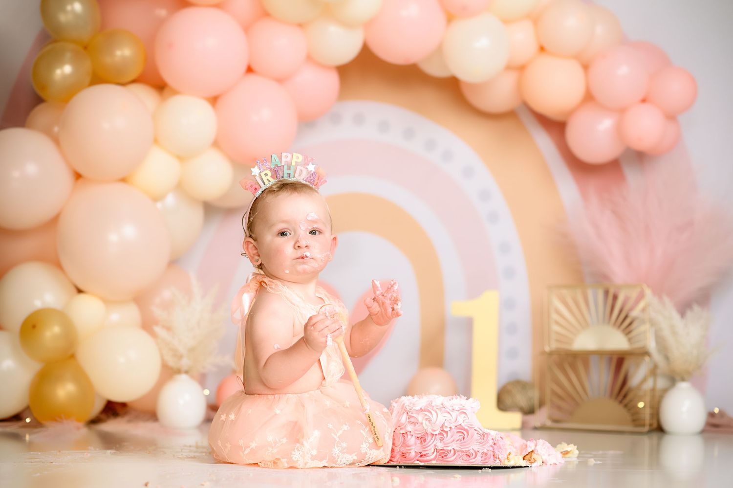 First birthday celebration setup with pink balloons and decorative number one.