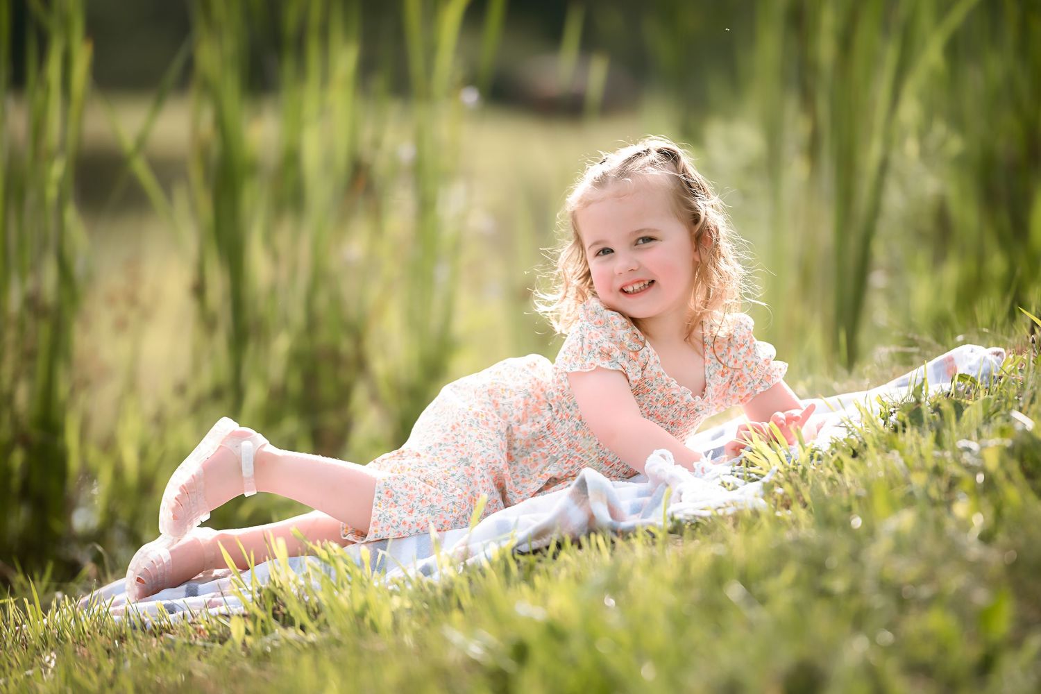 Children laying in a lush green field with wildflowers on a summer day.