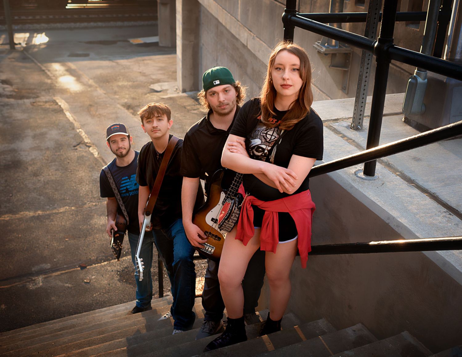 Band members posing in casual attire against industrial backdrop.