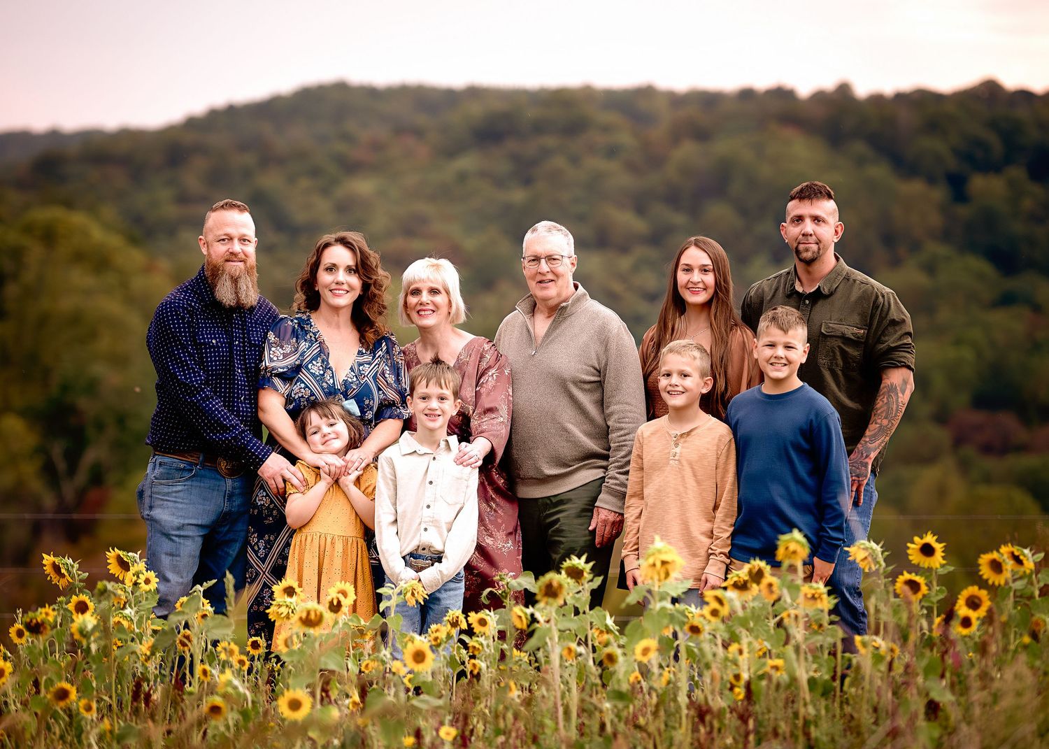 A large group poses together in a sunflower field during golden hour.