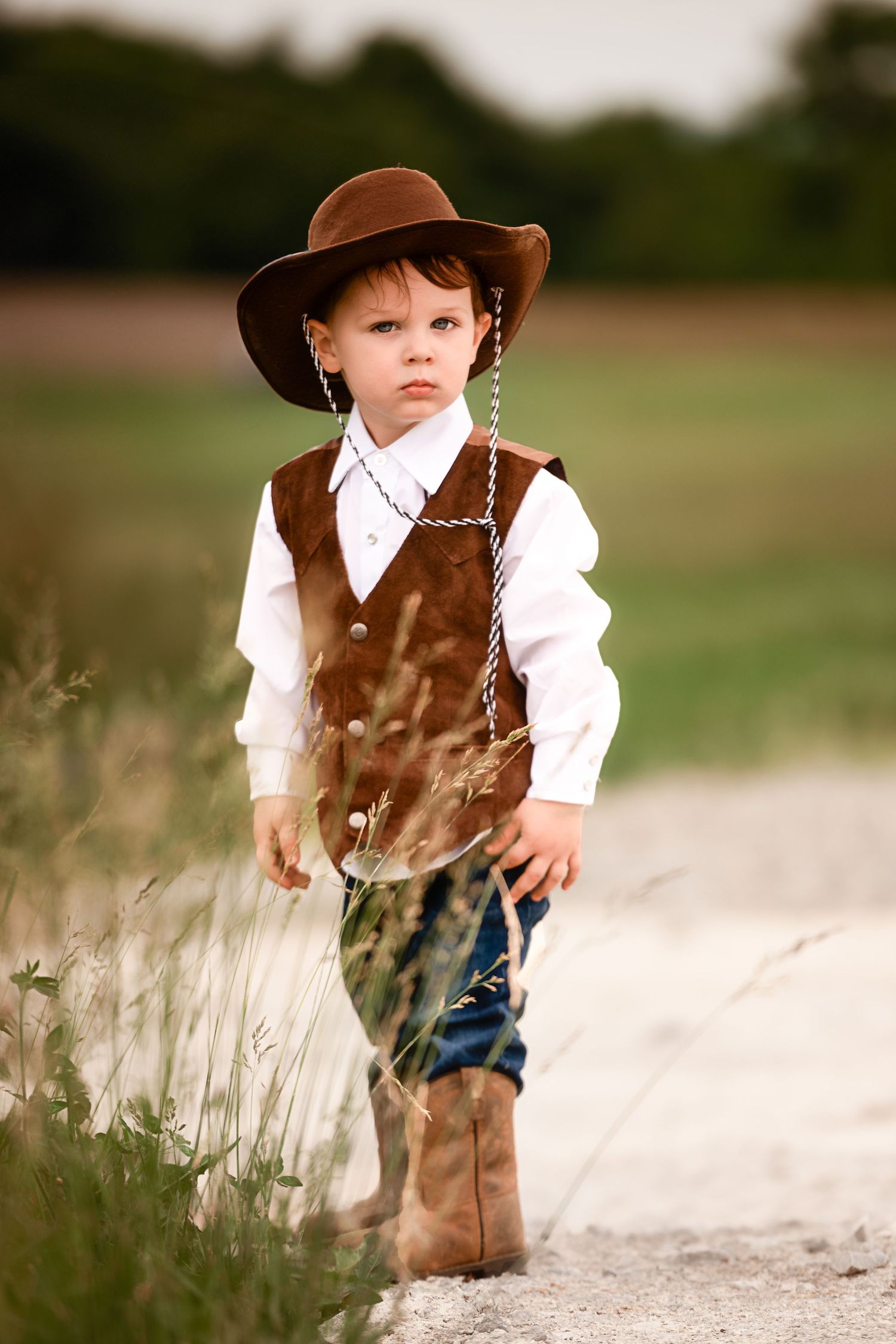 Western-style scene with cowboy attire against tall grass at sunset.