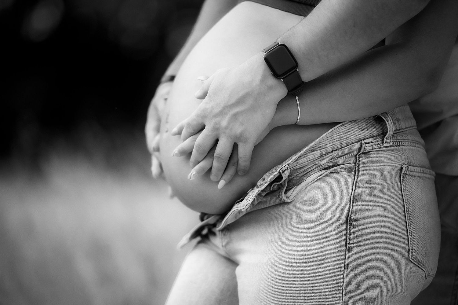 Black and white close-up series of hands touching a pregnant belly.