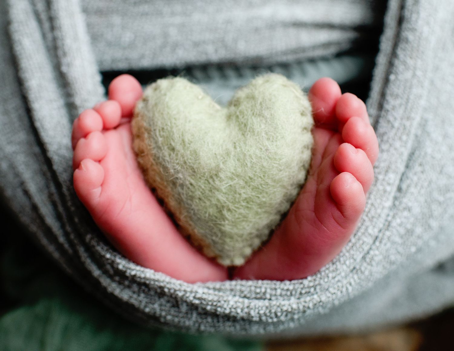 Small heart-shaped plush being held gently in tiny hands.
