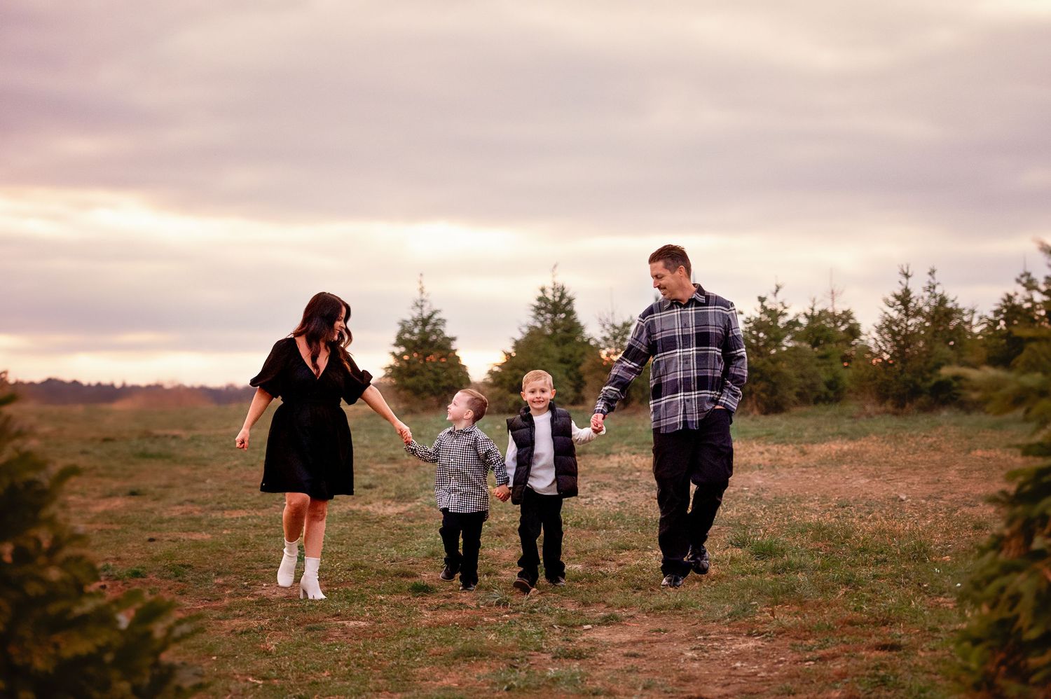 Family members spread out across hilltop meadow during sunset photoshoot.