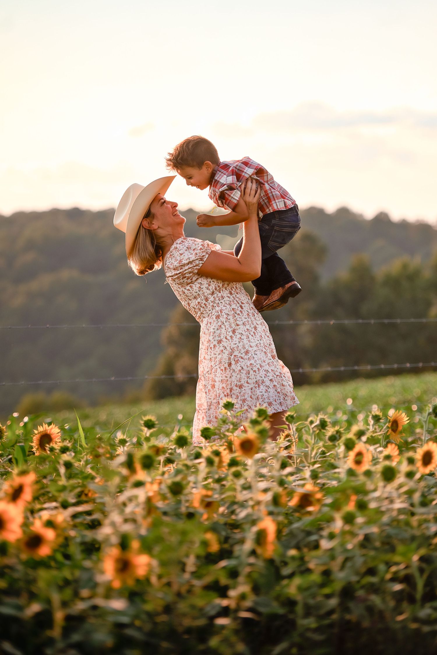 Romantic couple dancing in a sunflower field during golden hour sunset.