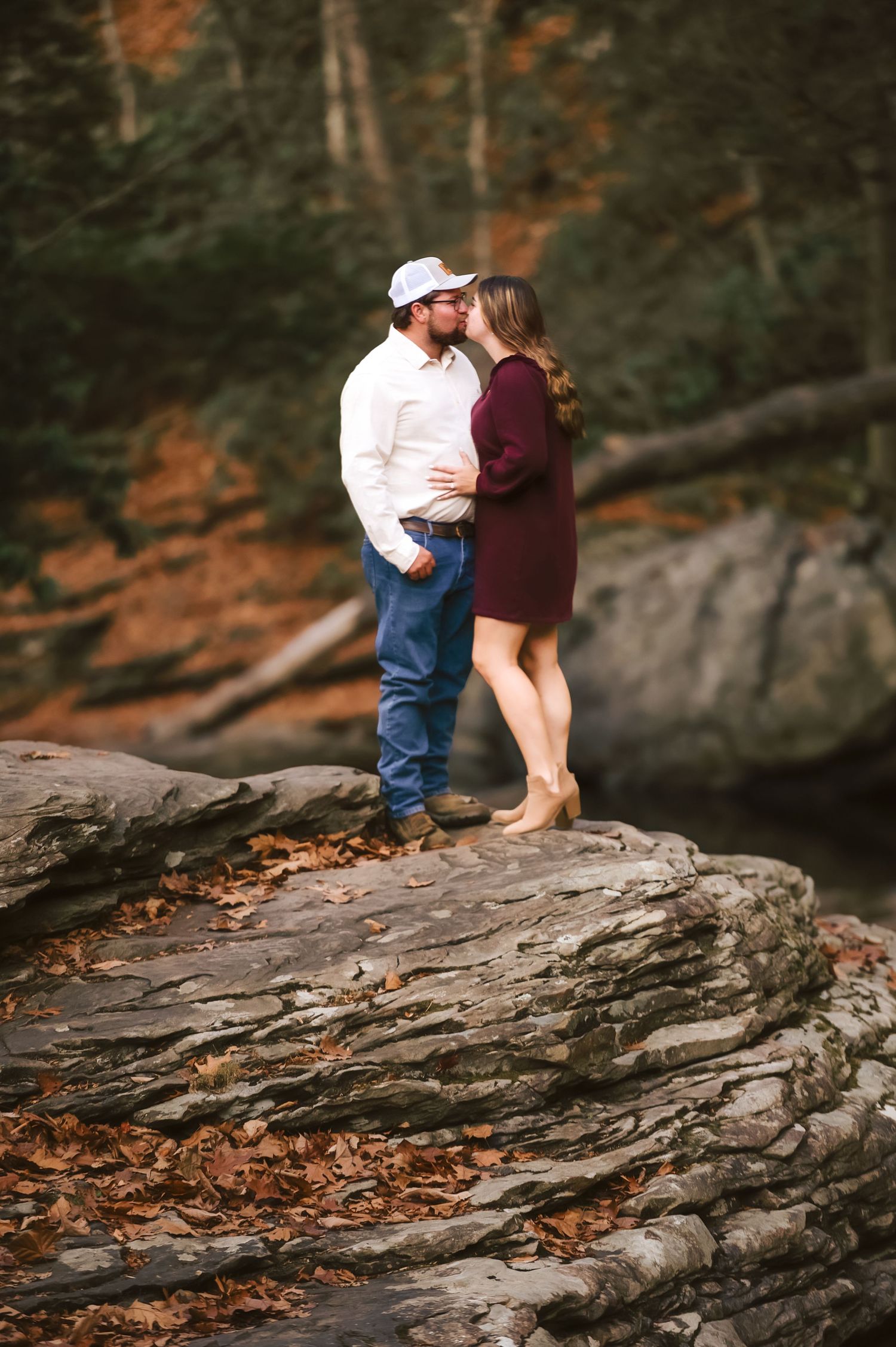 Romantic photoshoot on large rock formations surrounded by fall foliage.