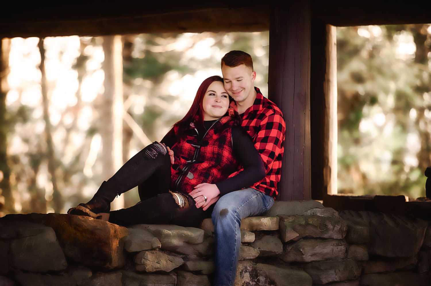Couple relaxing on stone wall during sunset photoshoot in nature.