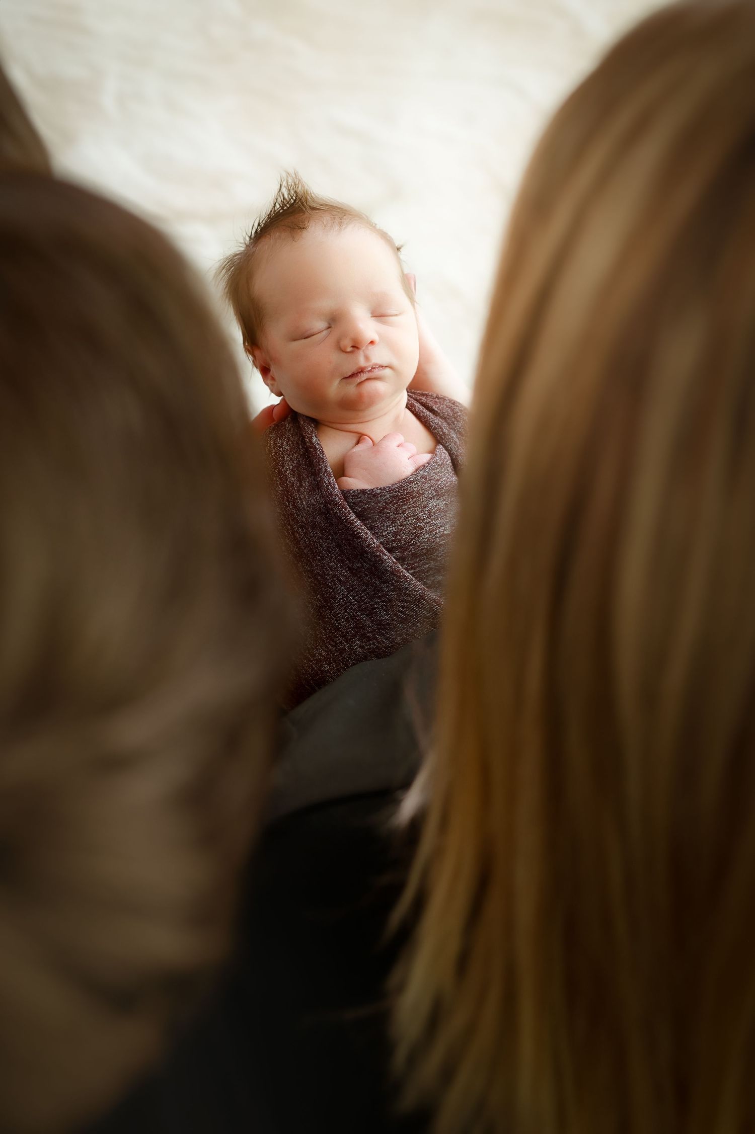 Intimate newborn photography session with soft focus and natural lighting.