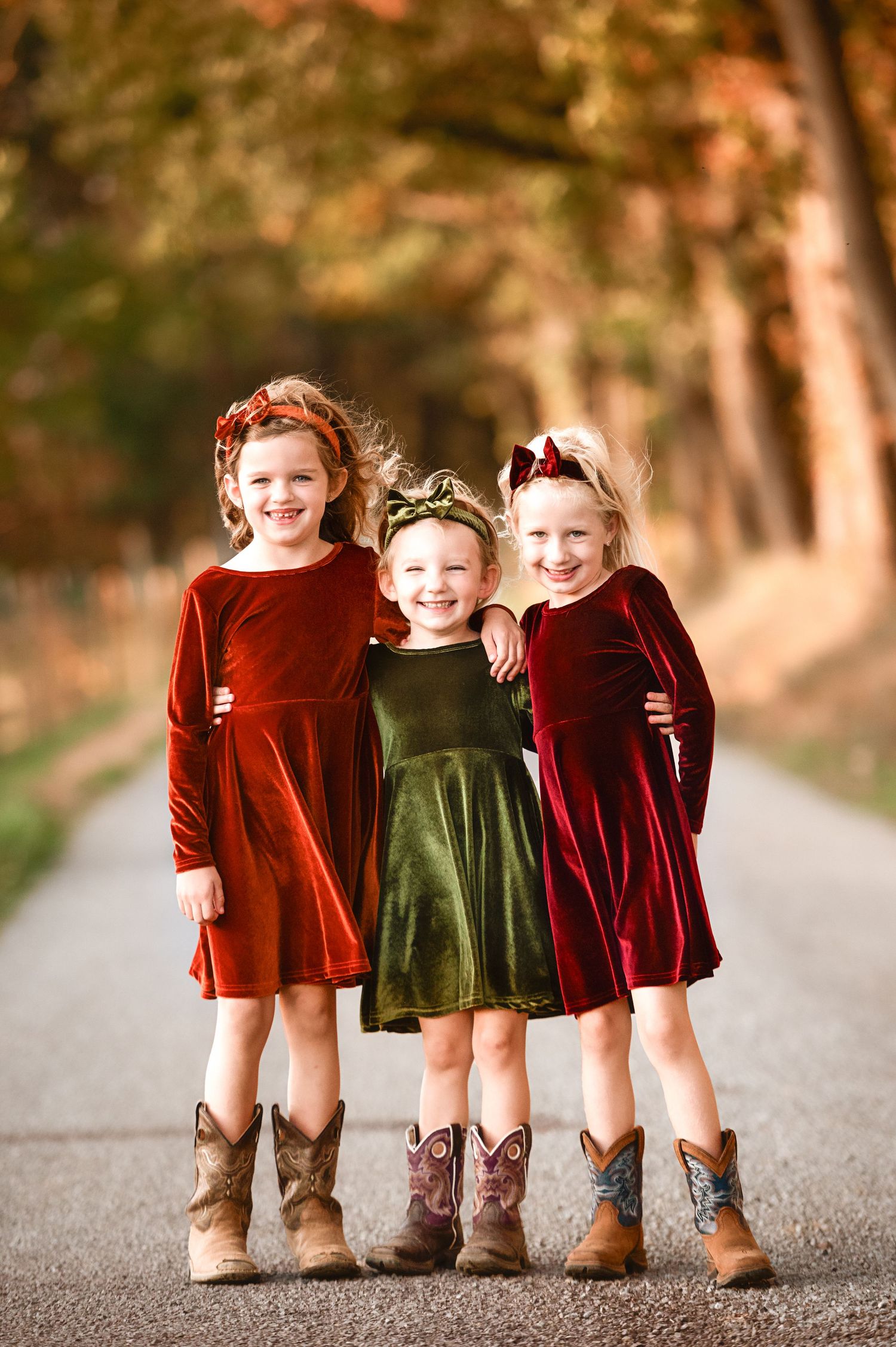 Three pairs of brown boots worn with velvet holiday dresses shown from the knees down.