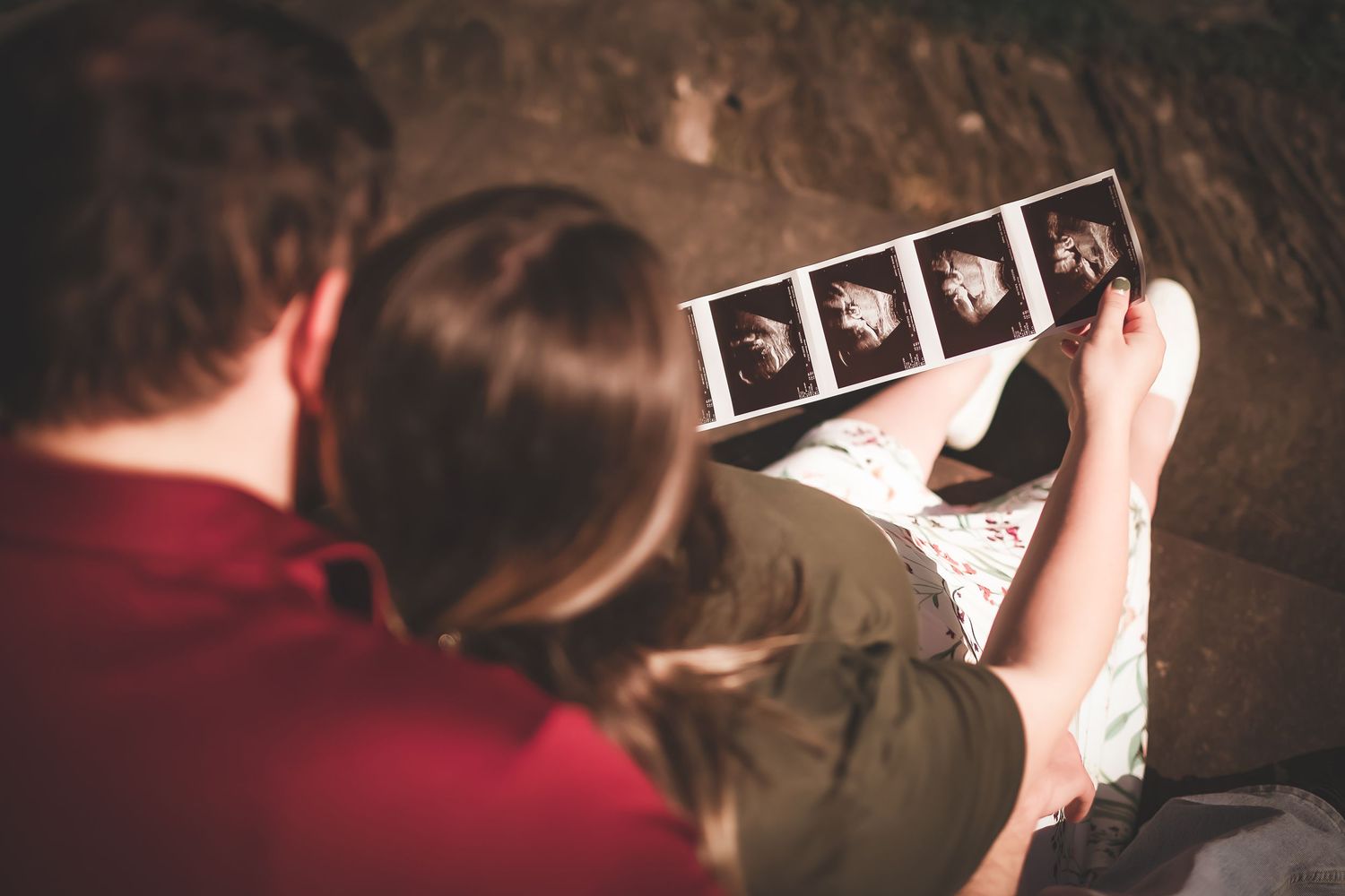 Close-up of hands holding ultrasound photos showing precious pregnancy moments.