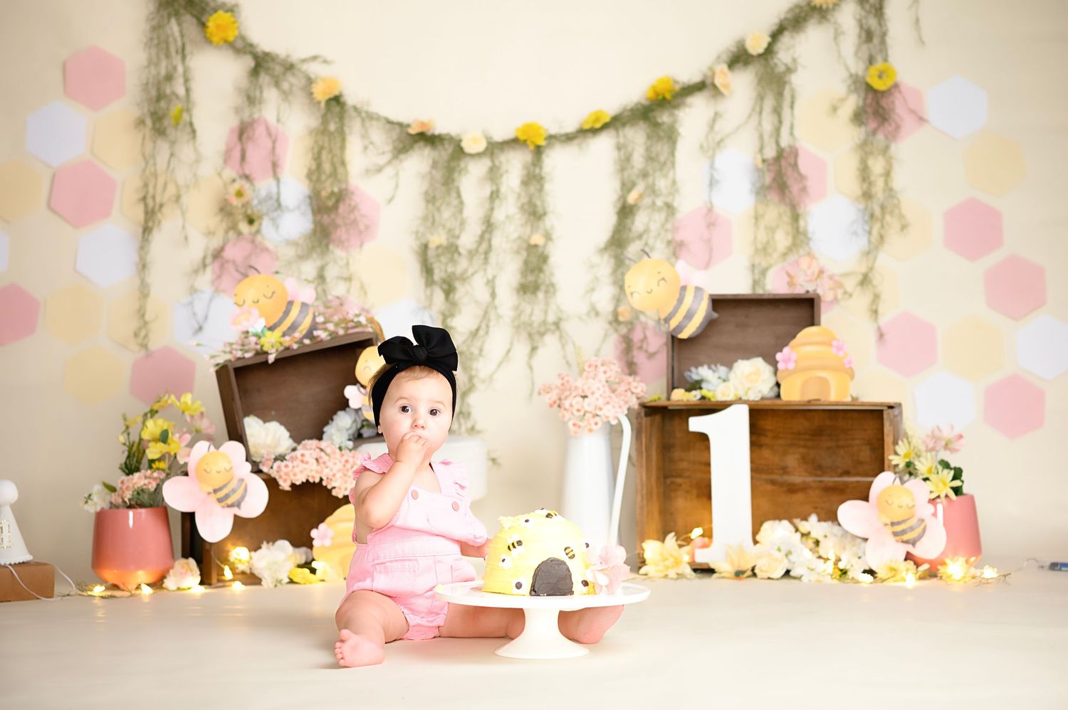 Pink and white party decoration setup with floral garlands and pastel balloons.