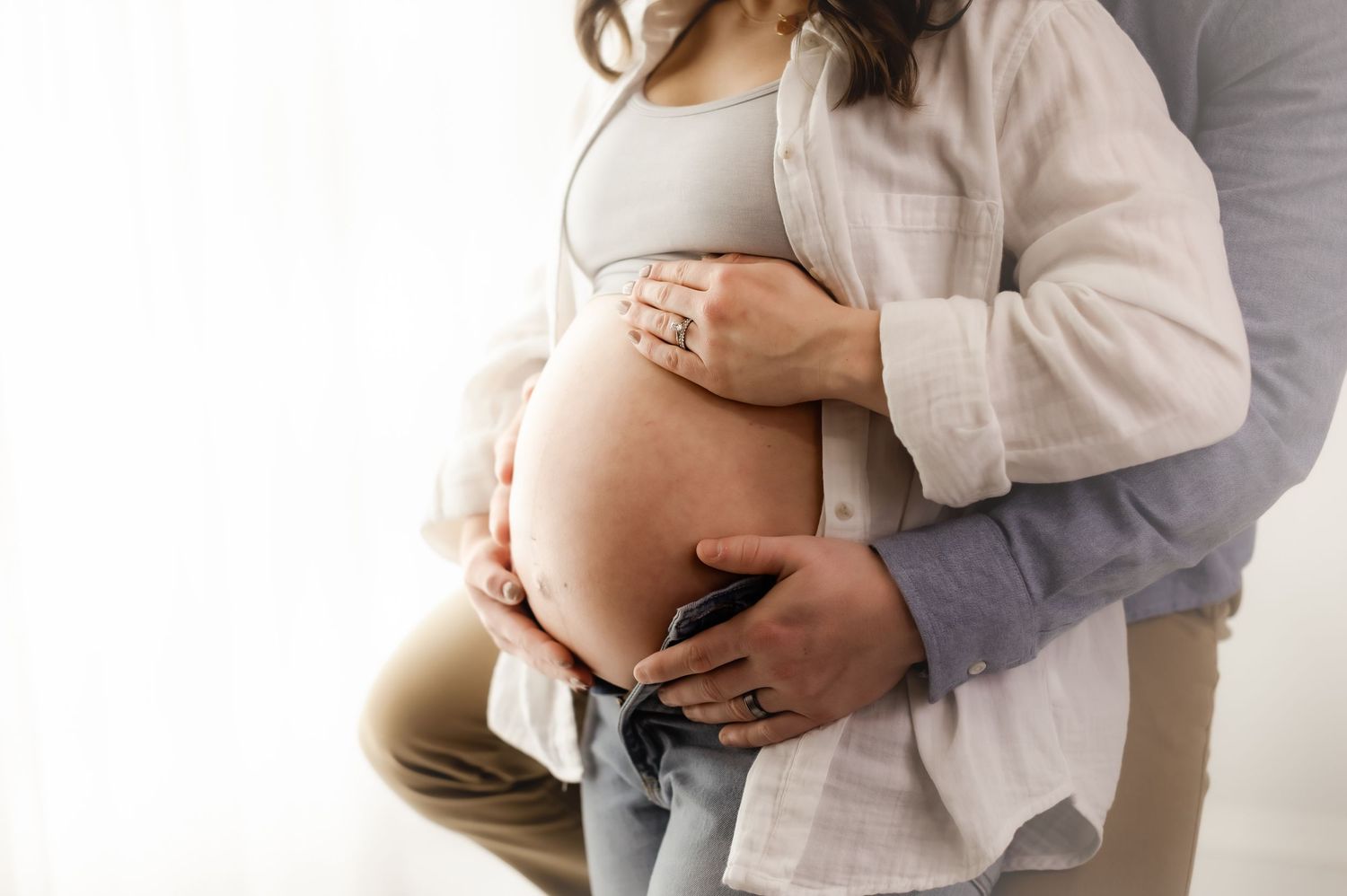 Intimate maternity photography session with soft lighting and neutral tones.