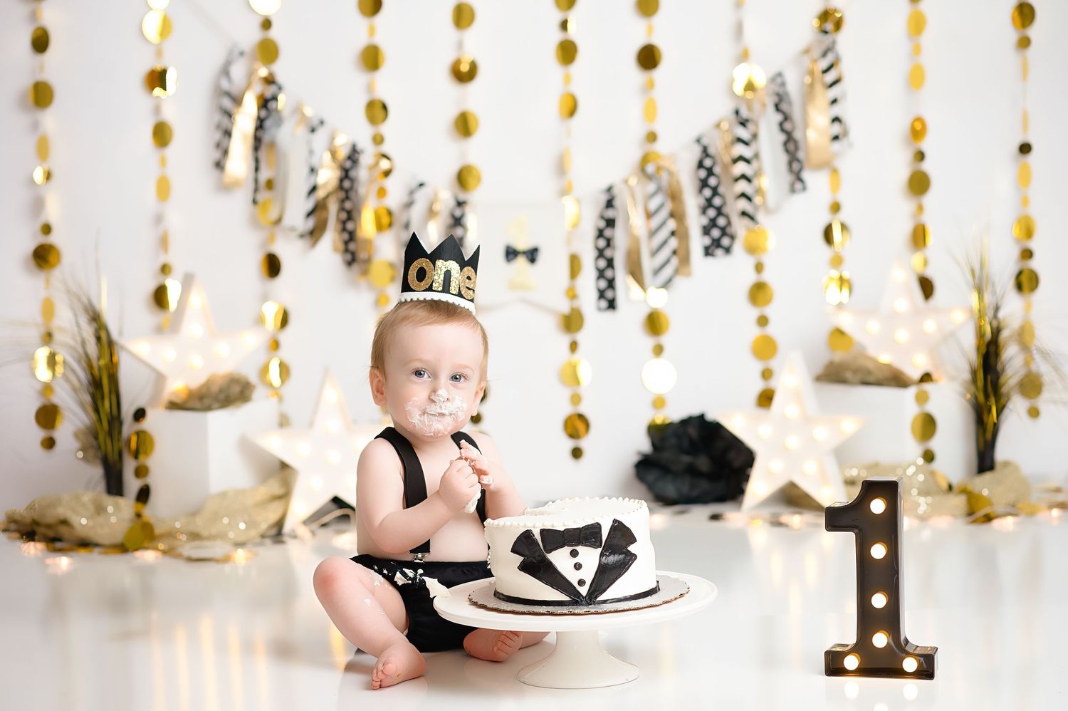 Gold star and circle garland decorations hanging against white backdrop for birthday celebration.