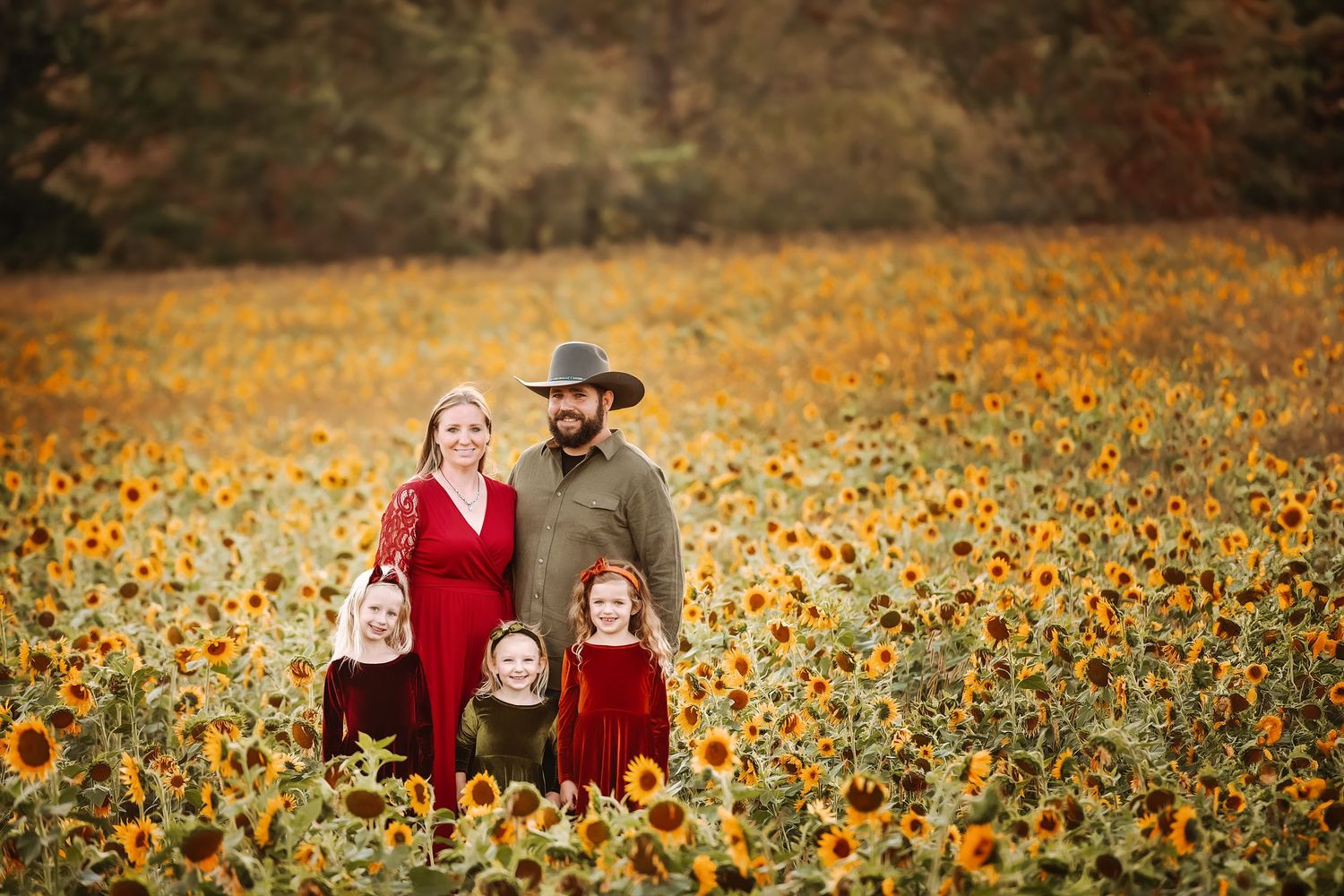 A family poses together in a vibrant field of yellow sunflowers.