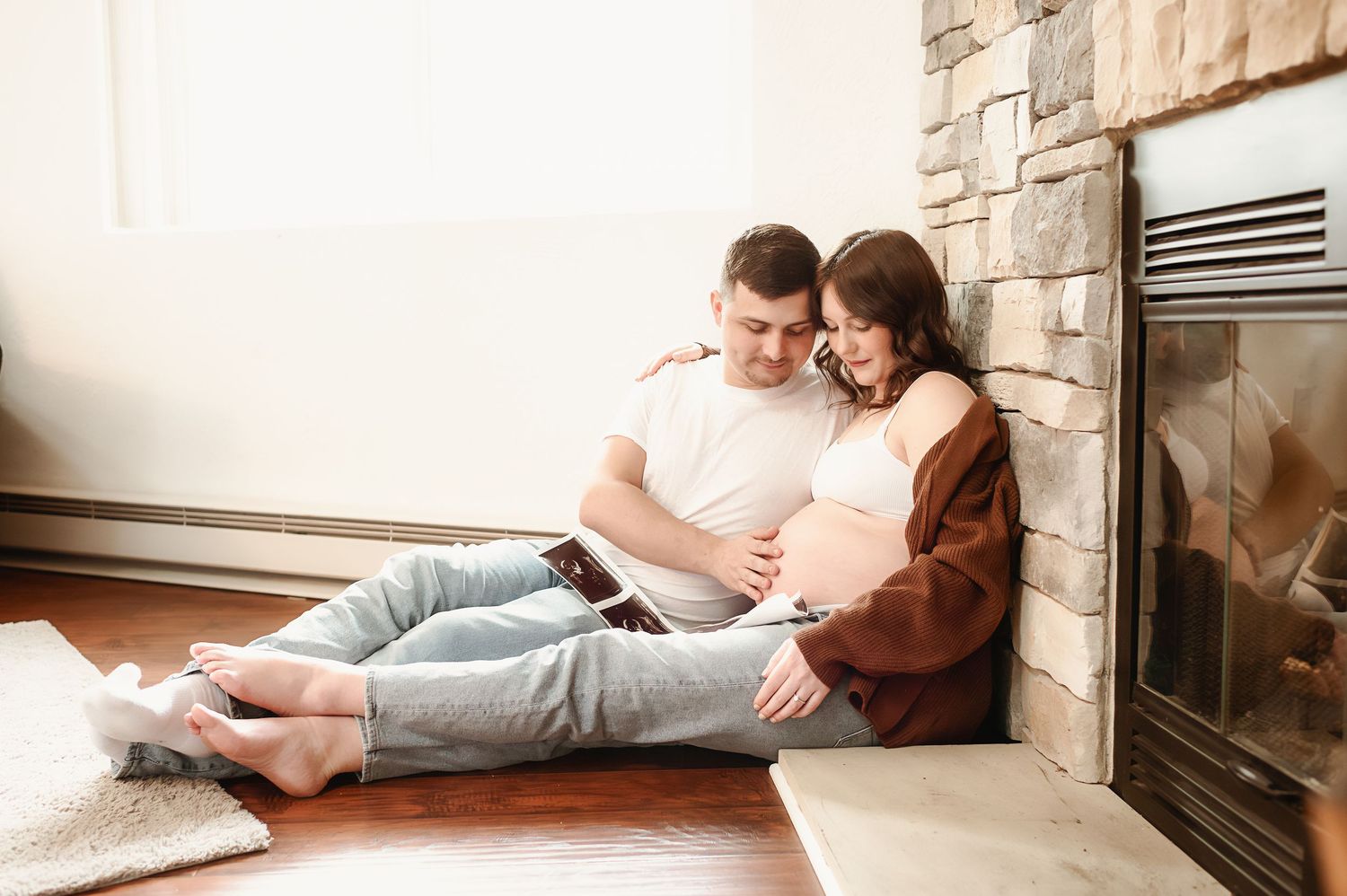 A cozy indoor maternity photo session near a stone fireplace.