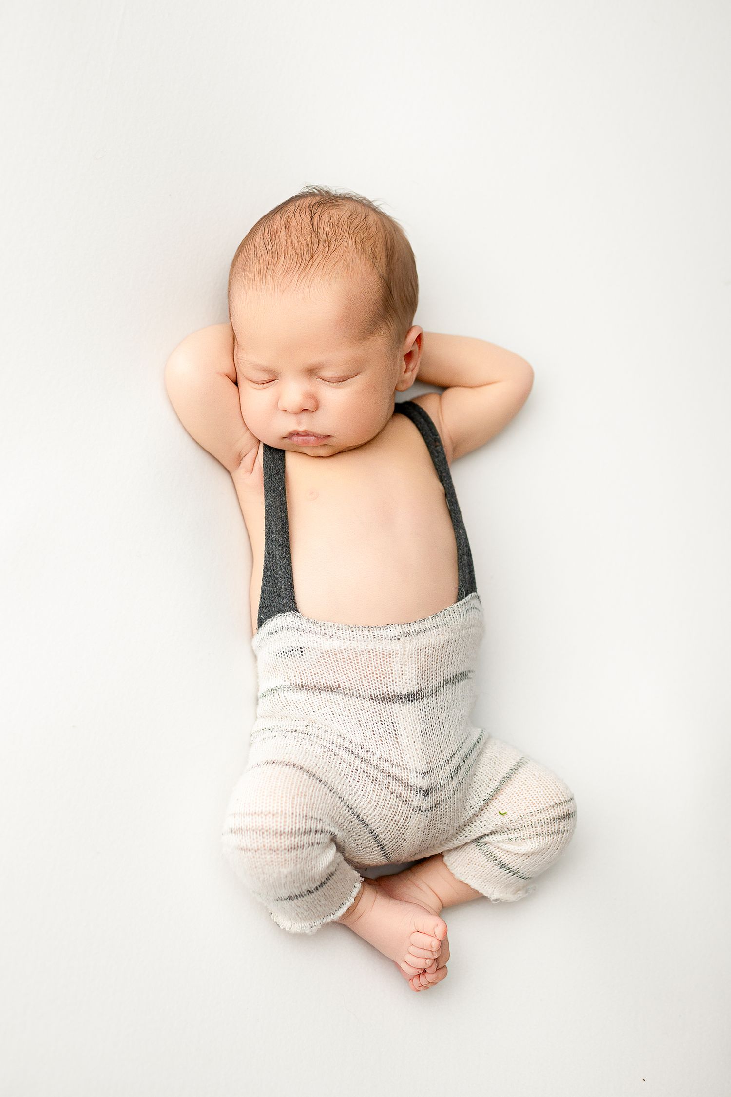 Newborn baby sleeping peacefully in white wrap on light background in artistic portrait series.