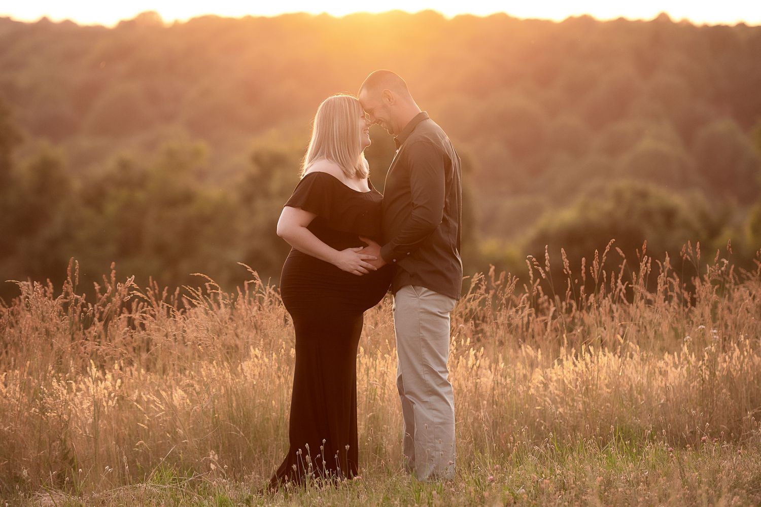 Multiple silhouettes embracing in a field during sunset.