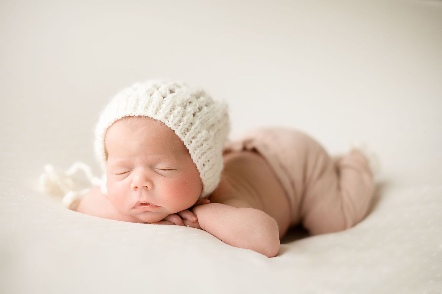 Peaceful newborn photography with soft white textures and gentle natural lighting.