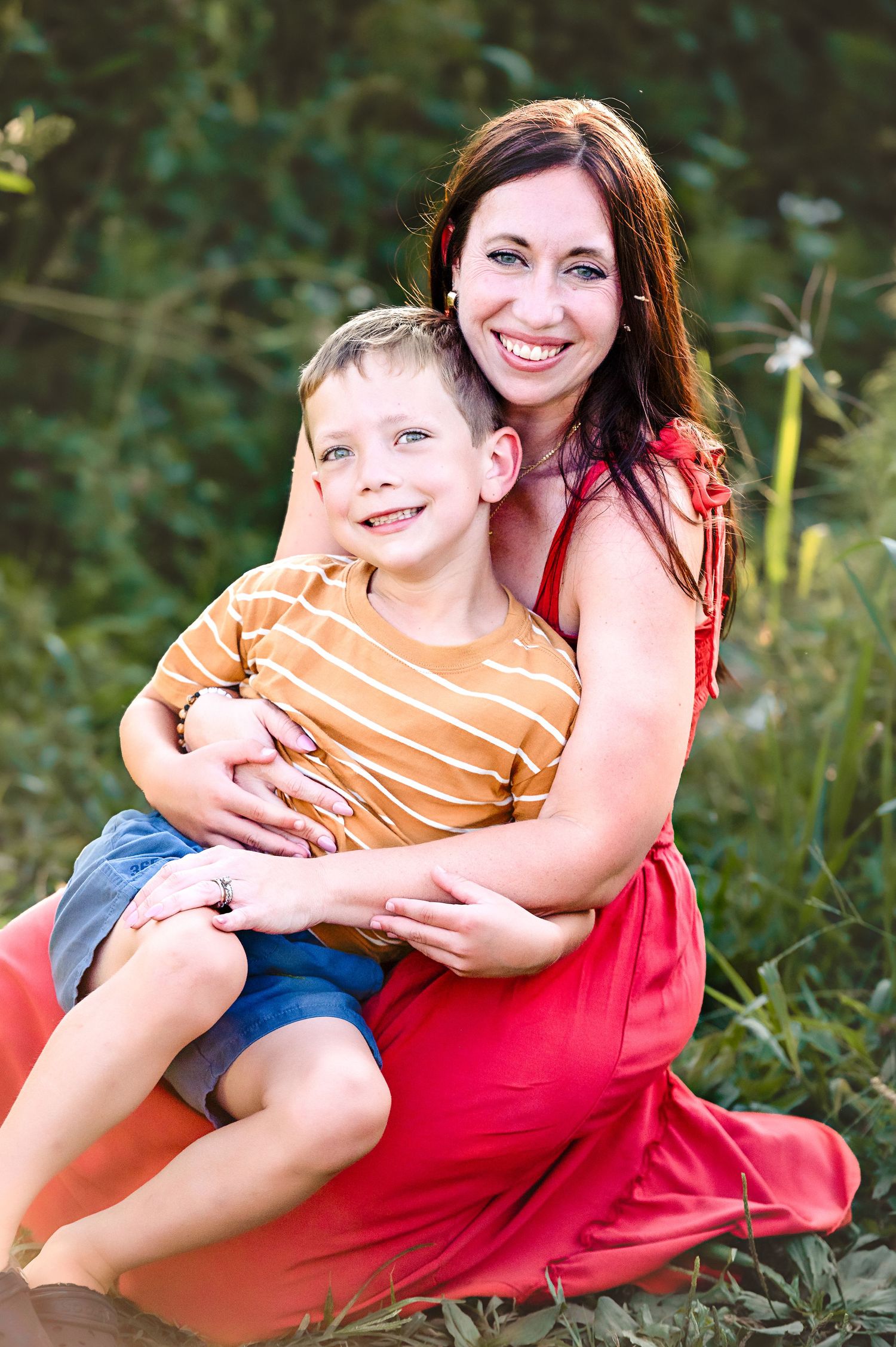 Candid family portrait in natural outdoor setting with greenery.