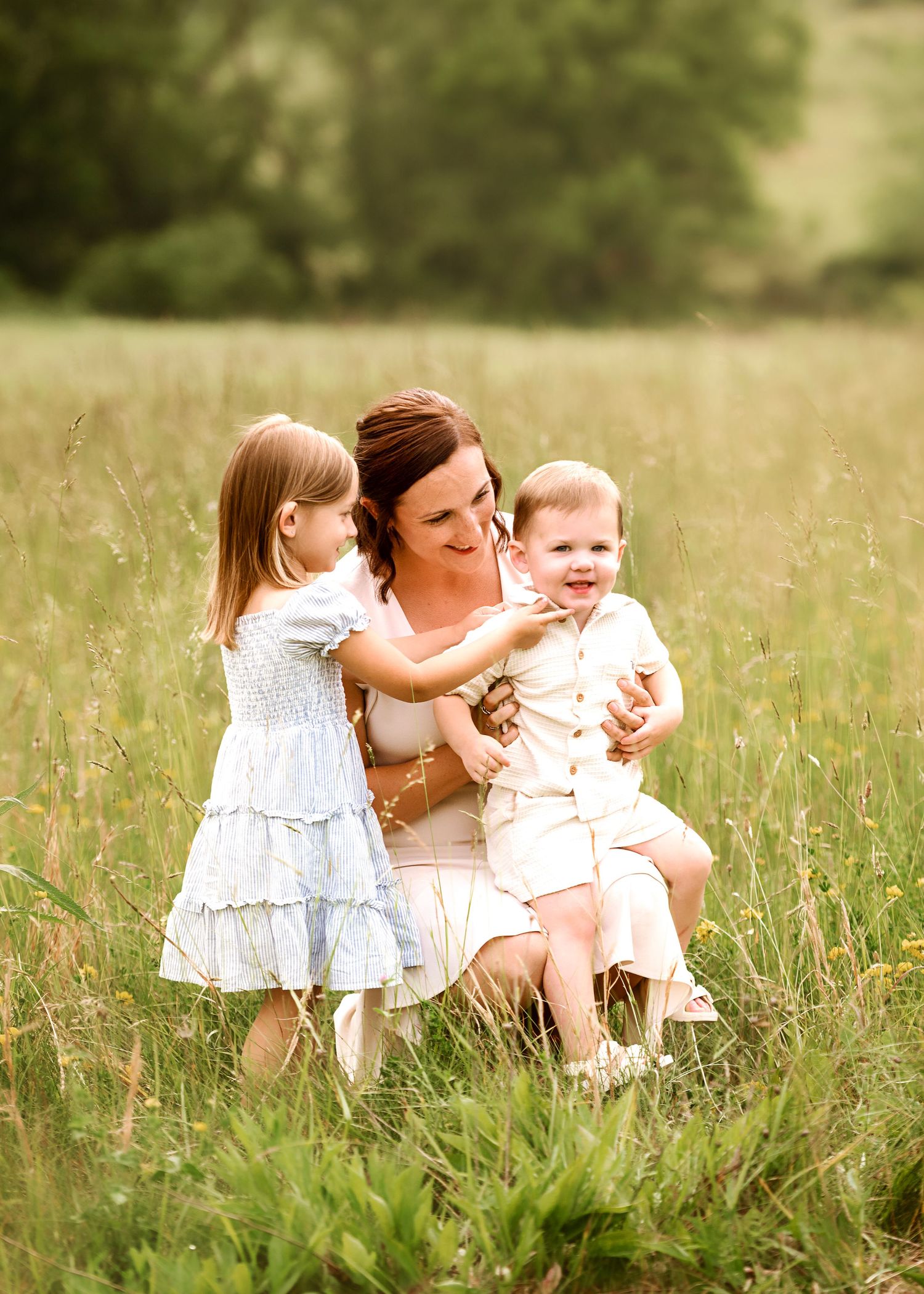 Tender family interactions while sitting together in a grassy summer meadow.