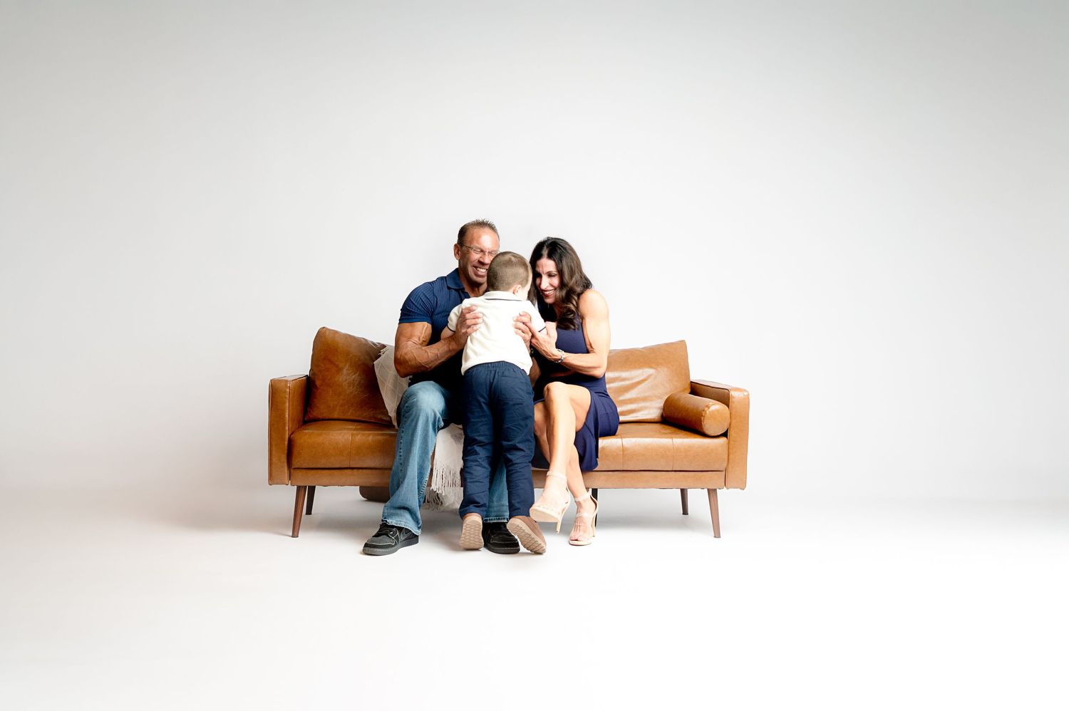 A modern brown leather couch photographed in a minimalist white studio setting.