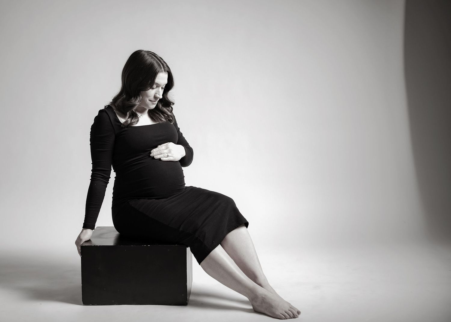 Minimalist maternity photography series in black and white against white backdrop.