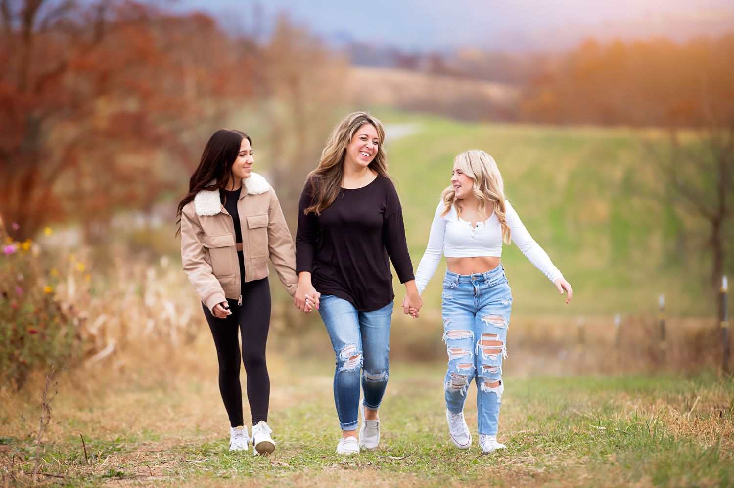 Friends walking together through an autumn field during golden hour.