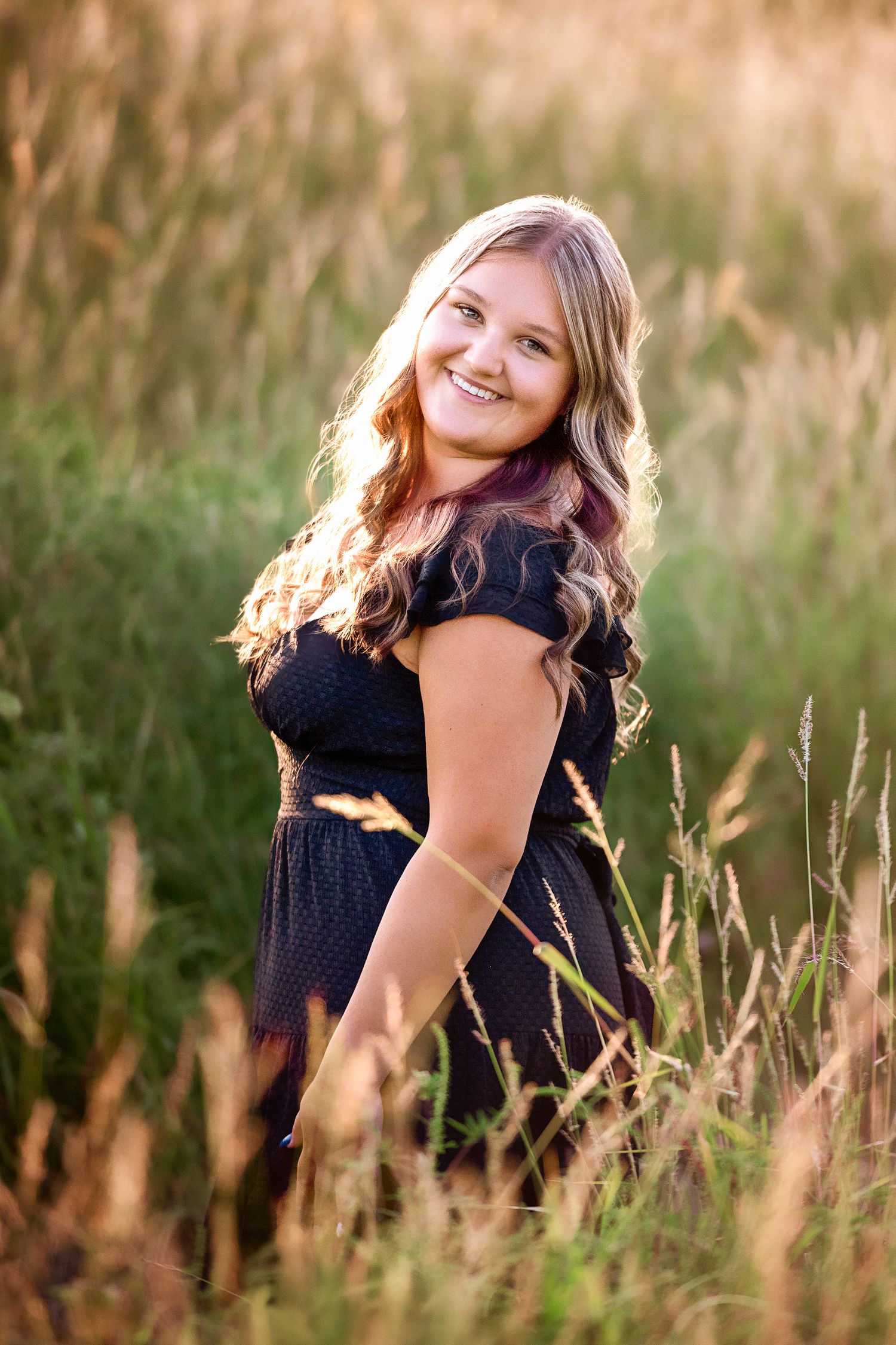 A portrait session in tall golden grass at sunset.