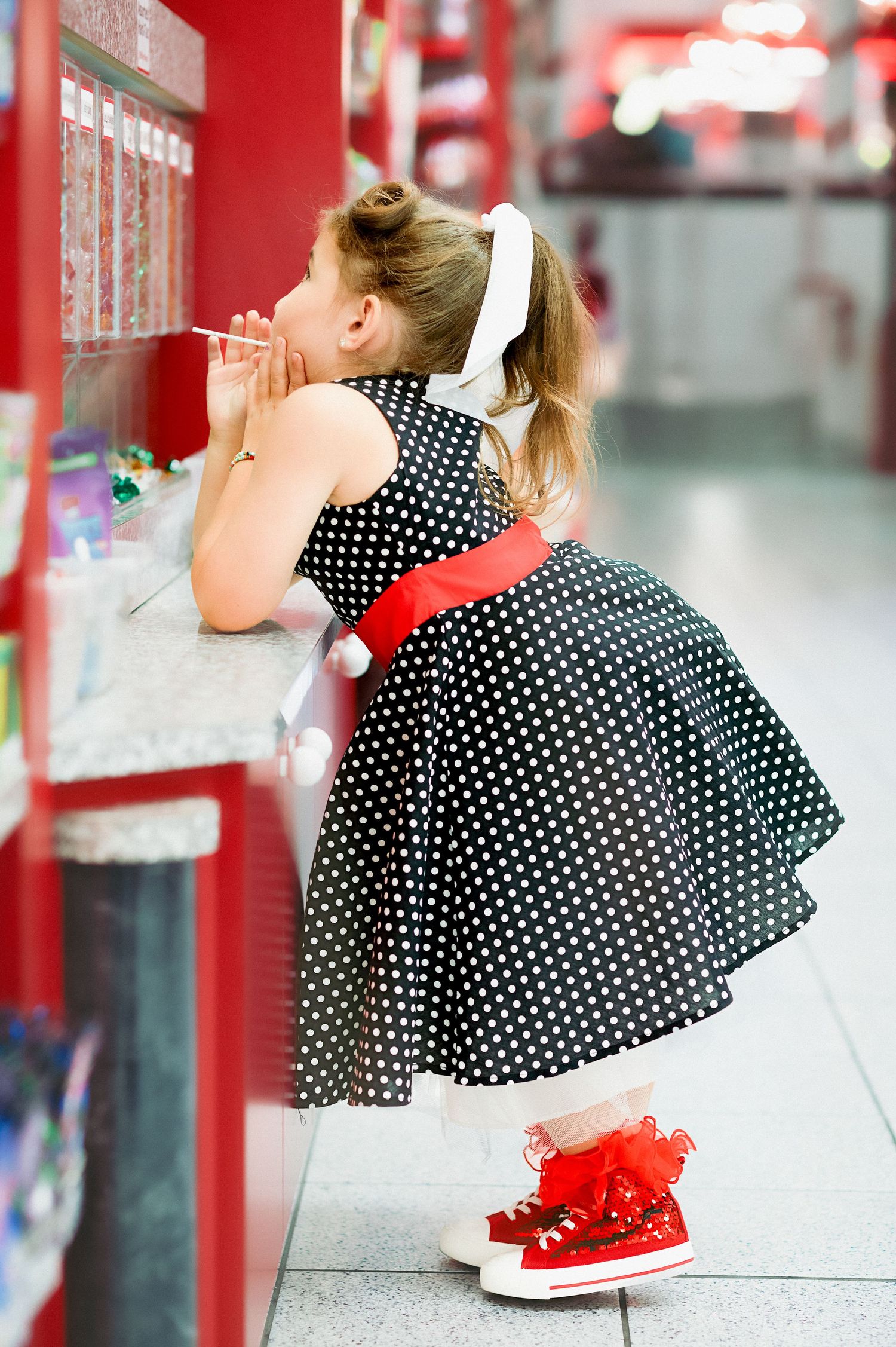 Polka dot dress photographed against red and white retail interior.