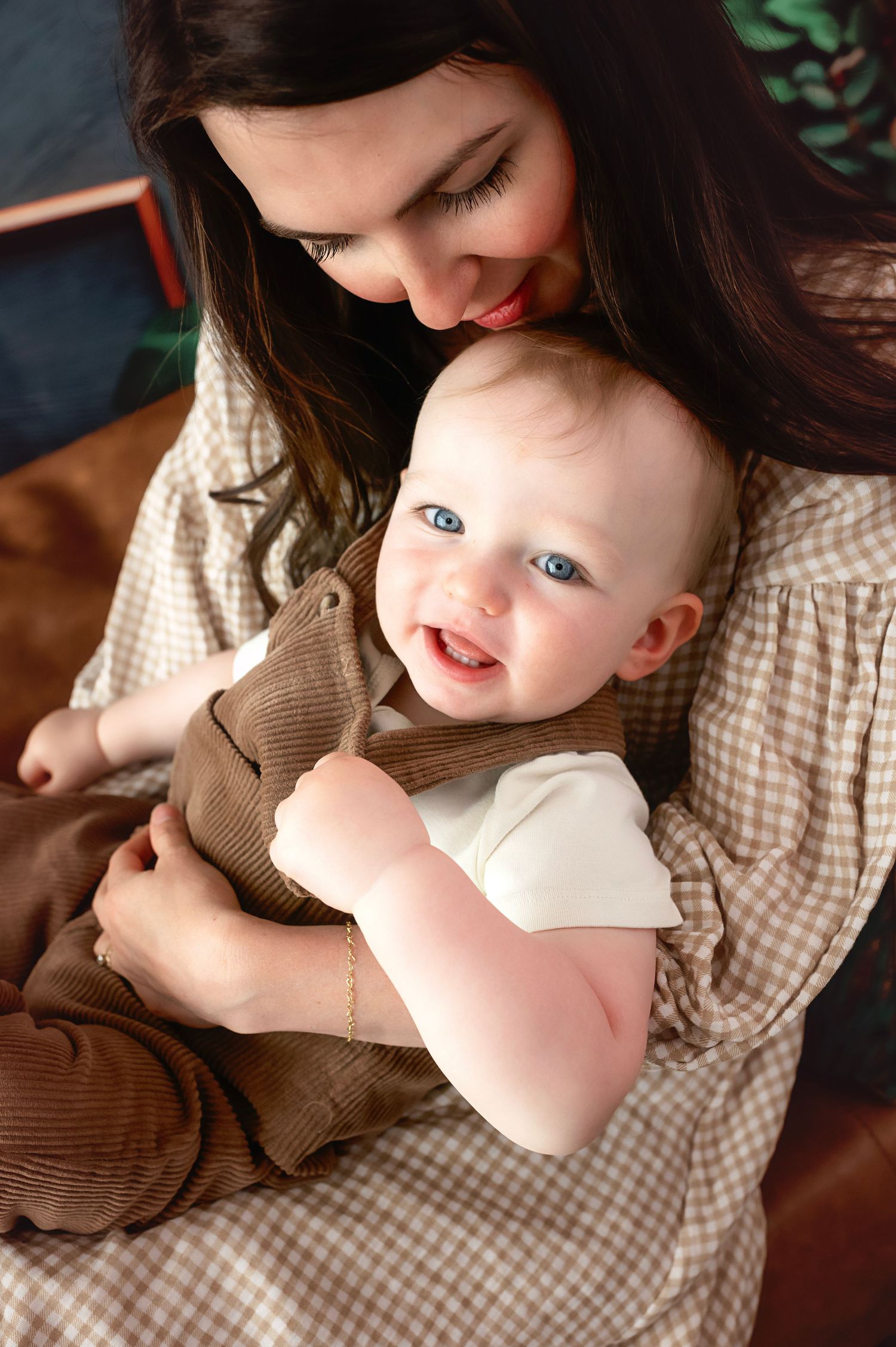 Tender moment between parent and baby in casual brown and plaid clothing.