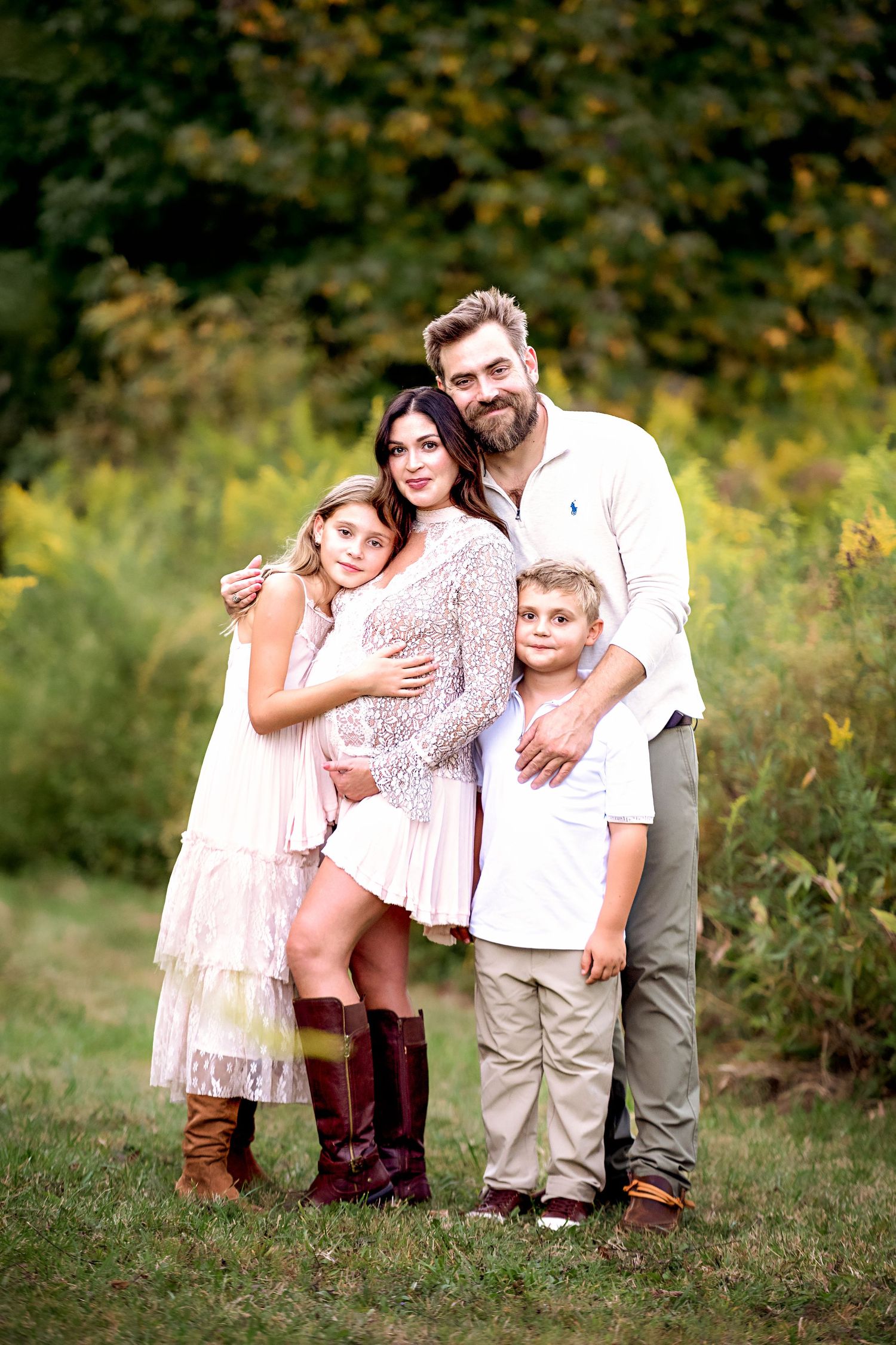 Family portrait session in casual attire with brown boots against natural outdoor setting.