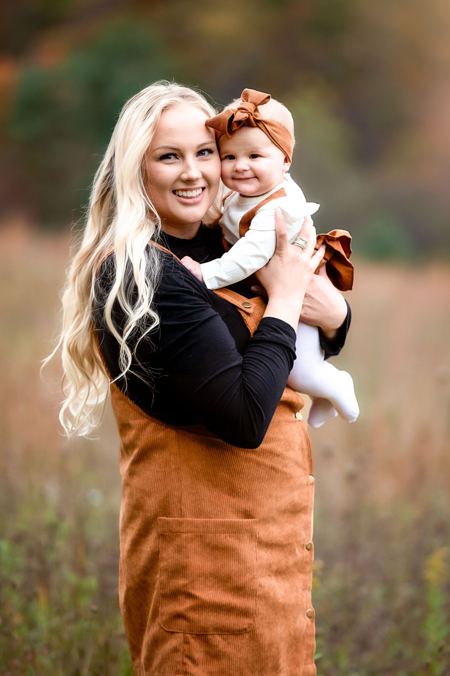 Sweet moment between caregiver and baby in autumn setting wearing coordinated brown outfits.