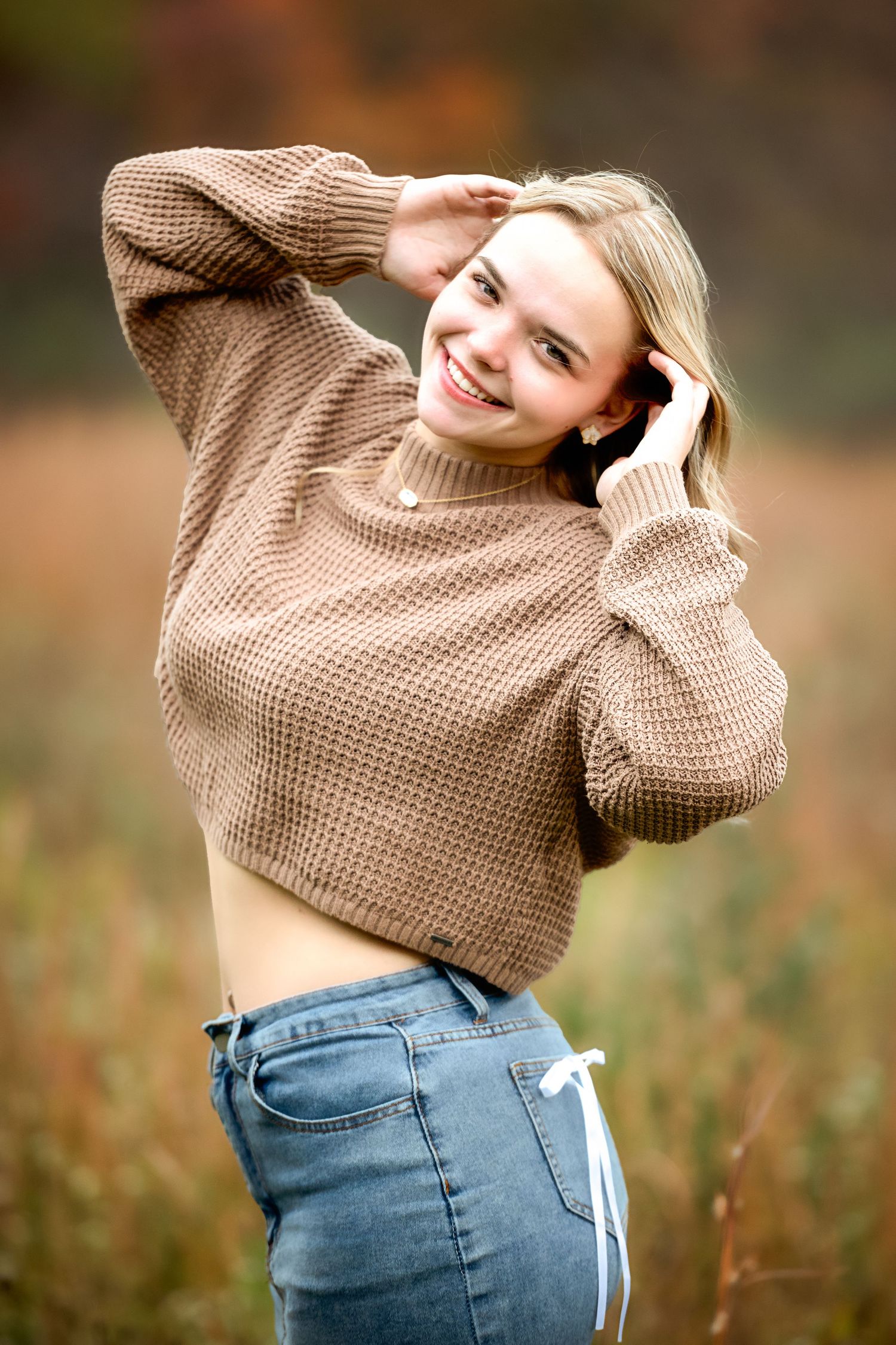 A casual autumn outfit featuring a beige knit sweater and blue jeans.