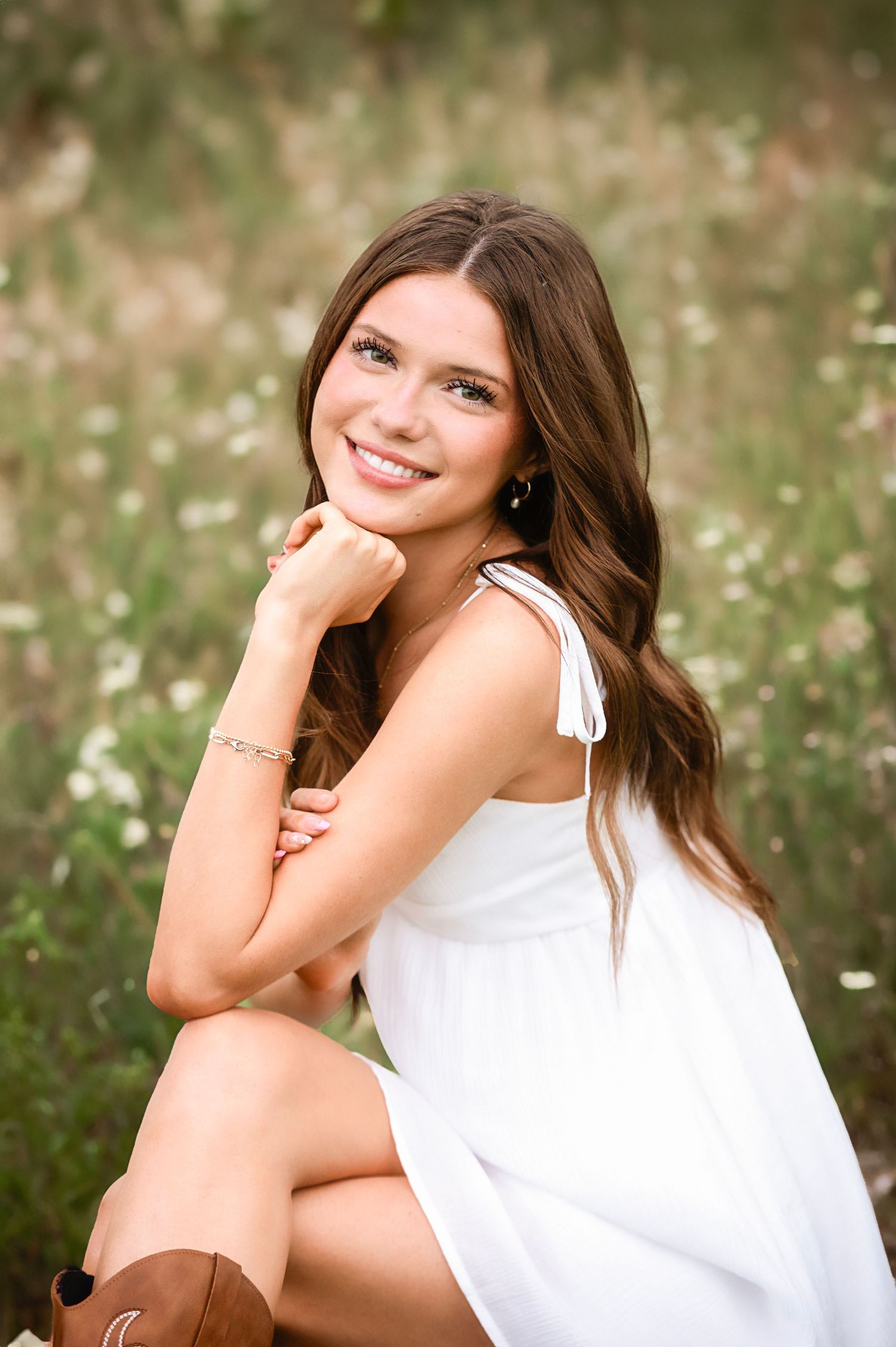 Portrait series in a field of wildflowers with a white sleeveless top and natural lighting.