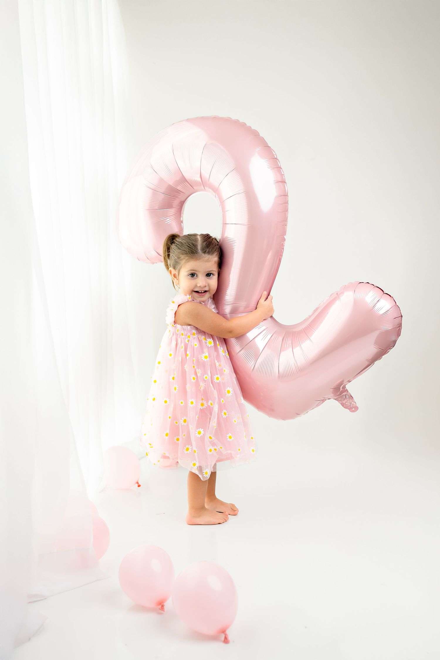 Studio photography setup with pink heart-shaped balloons against a white backdrop.