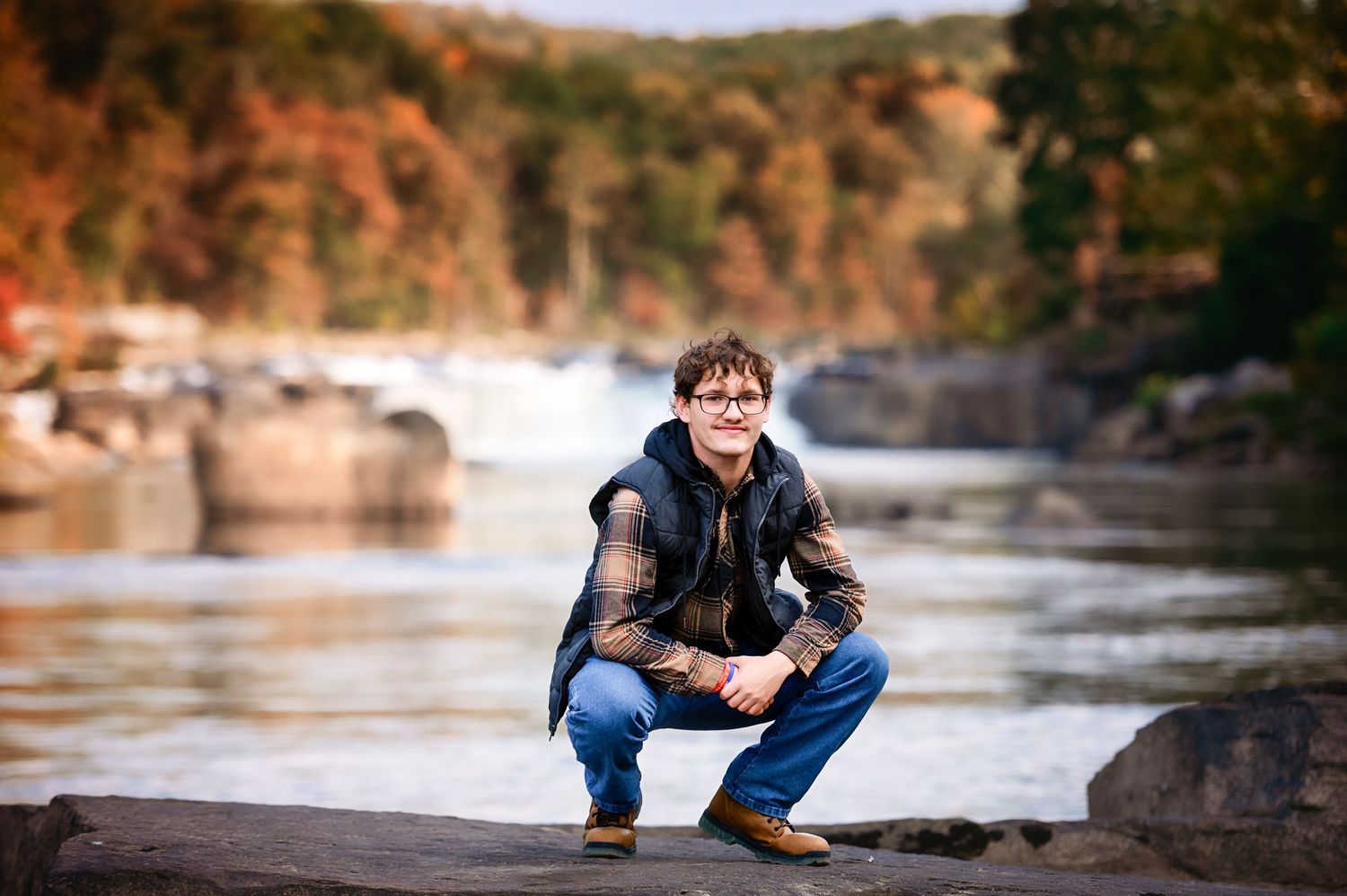 Outdoor portrait series near a rocky riverbank with fall colors.