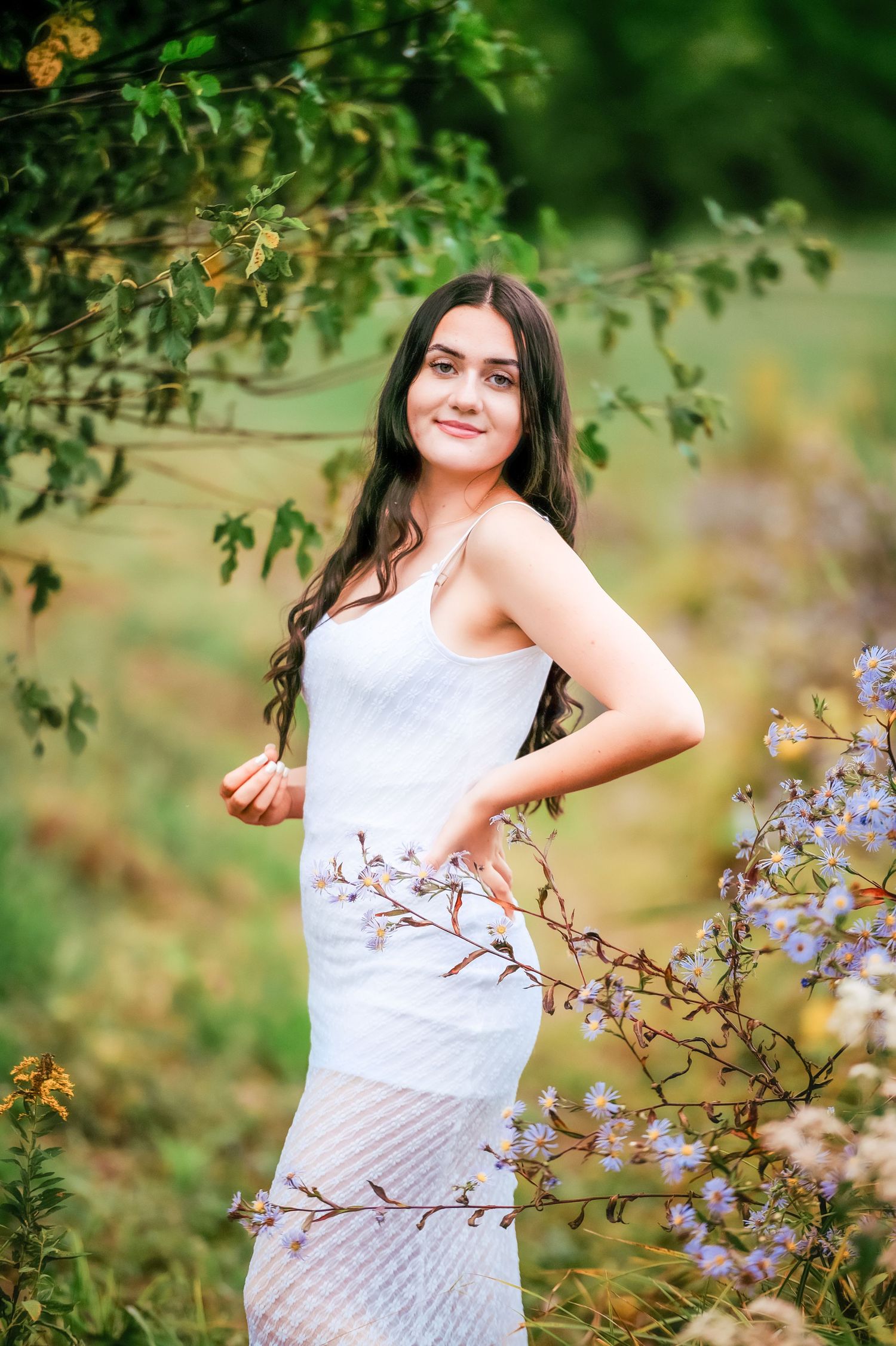 Portrait session in a garden with blooming purple flowers and green foliage.