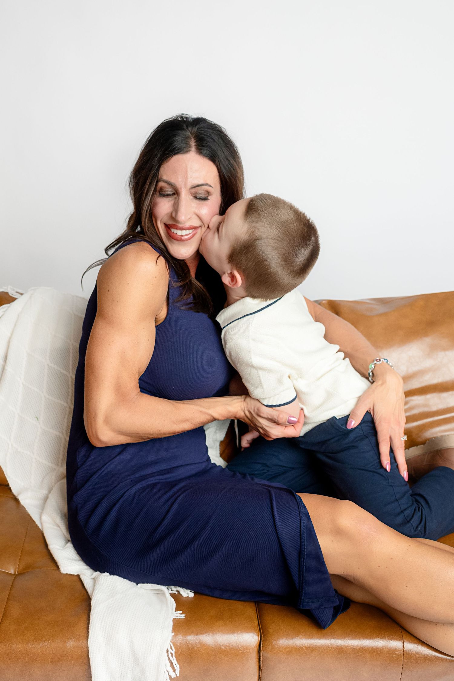 Intimate lifestyle photos of parent and child cuddling on leather couch.