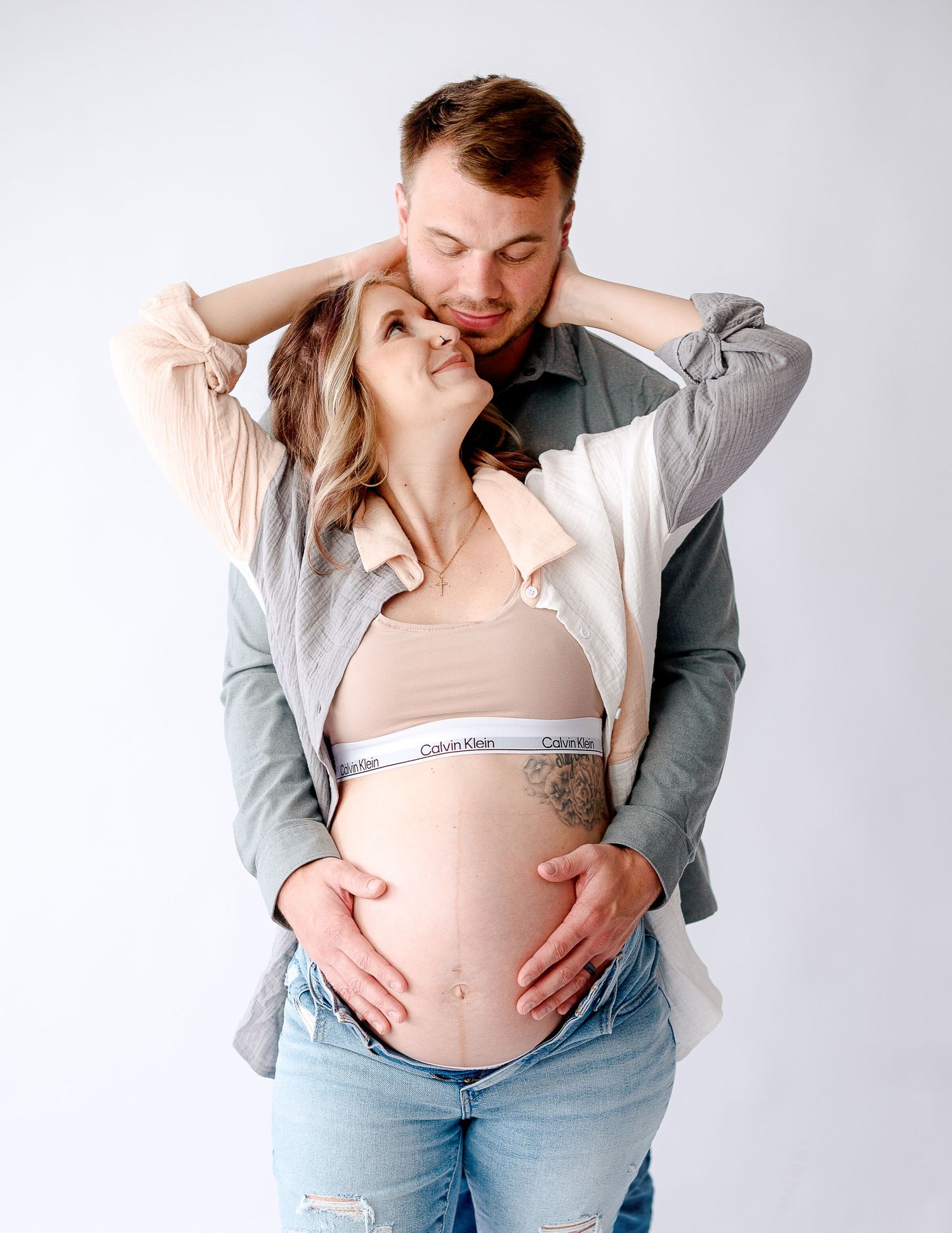 Casual maternity photos showing couple in denim and neutral colors.