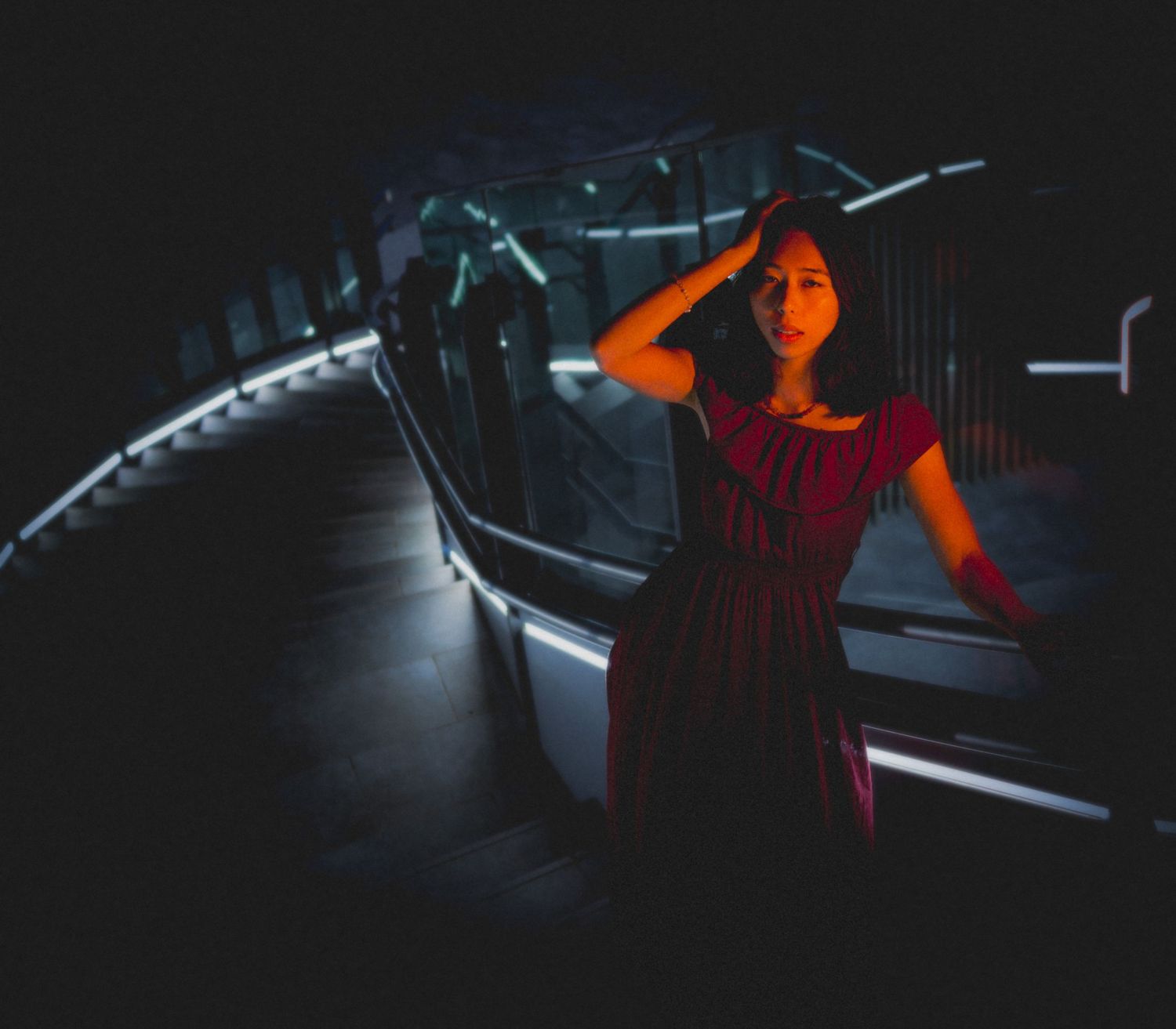 Silhouette against neon lights in a dark moody setting with red dress.