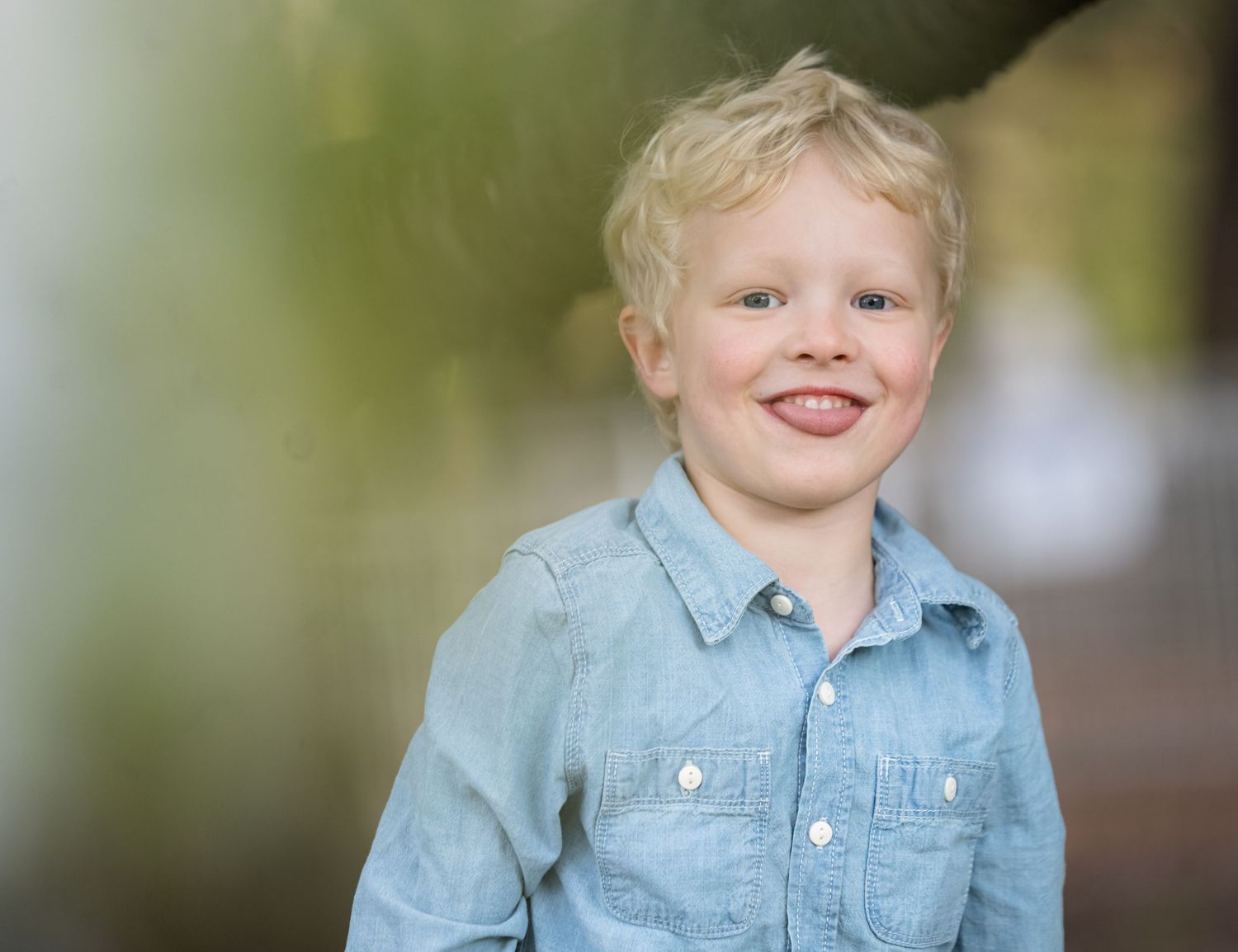 Candid portrait of a young child in denim shirt with natural lighting.