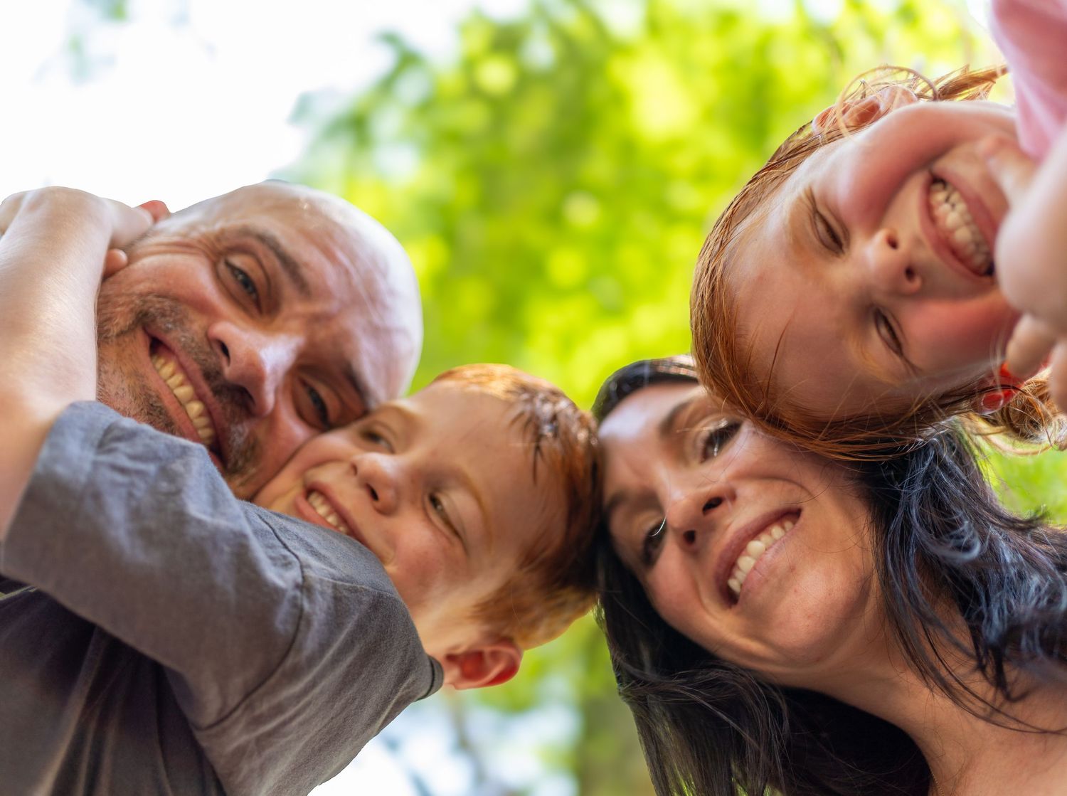 A collage of people laughing and smiling in a row against a bright green leafy background.