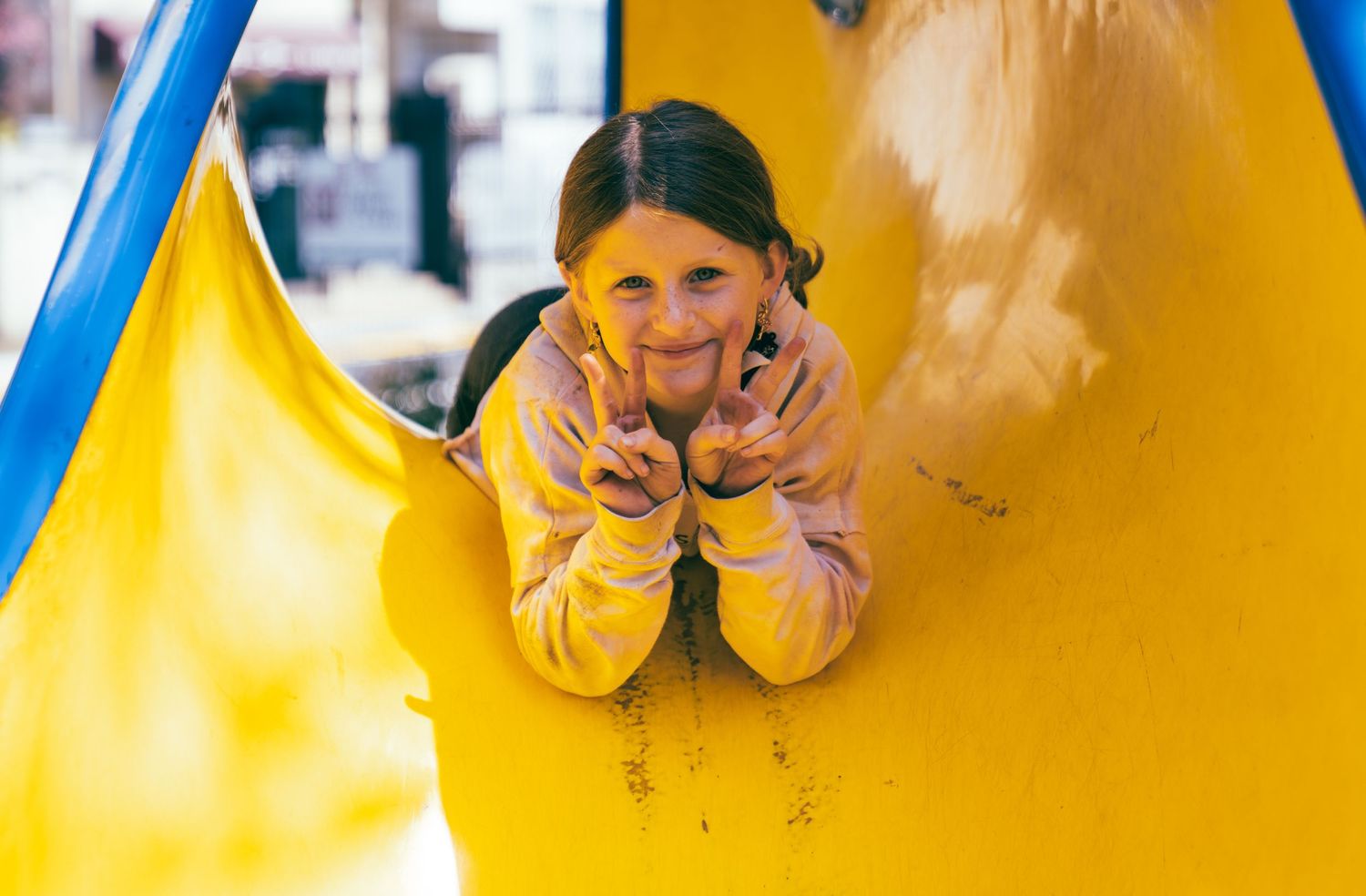 Child playing on yellow playground equipment wearing yellow sweater.